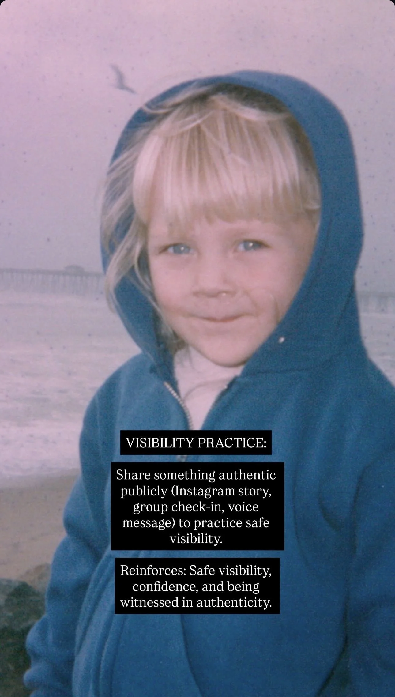 A young child with light blonde hair and blue eyes wearing a blue hoodie, standing outdoors near the beach with a pier and a seagull in the background. There is a black box with white text overlayed on the bottom right of the image.