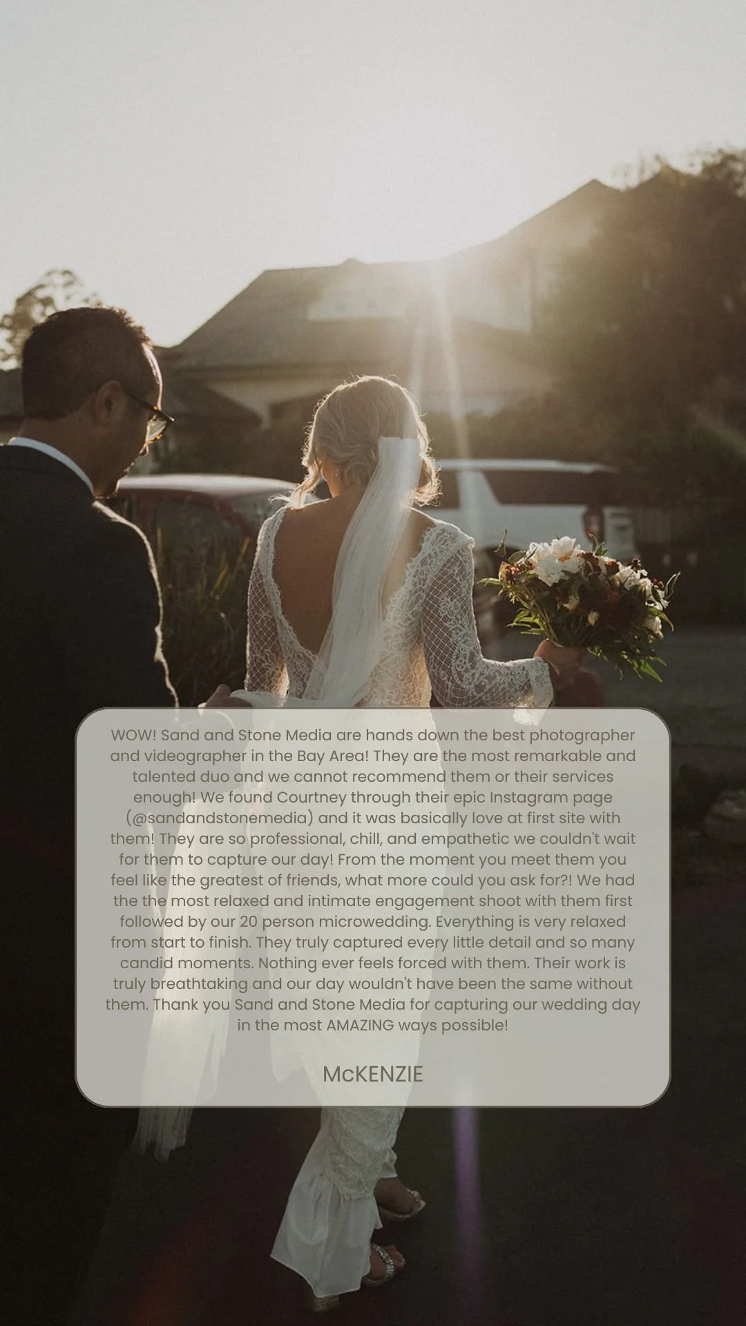 Photograph of a bride in a lace wedding dress holding a bouquet, walking outdoors at sunset with a man in a suit, likely her groom, near her. The scene features backlighting from the setting sun.