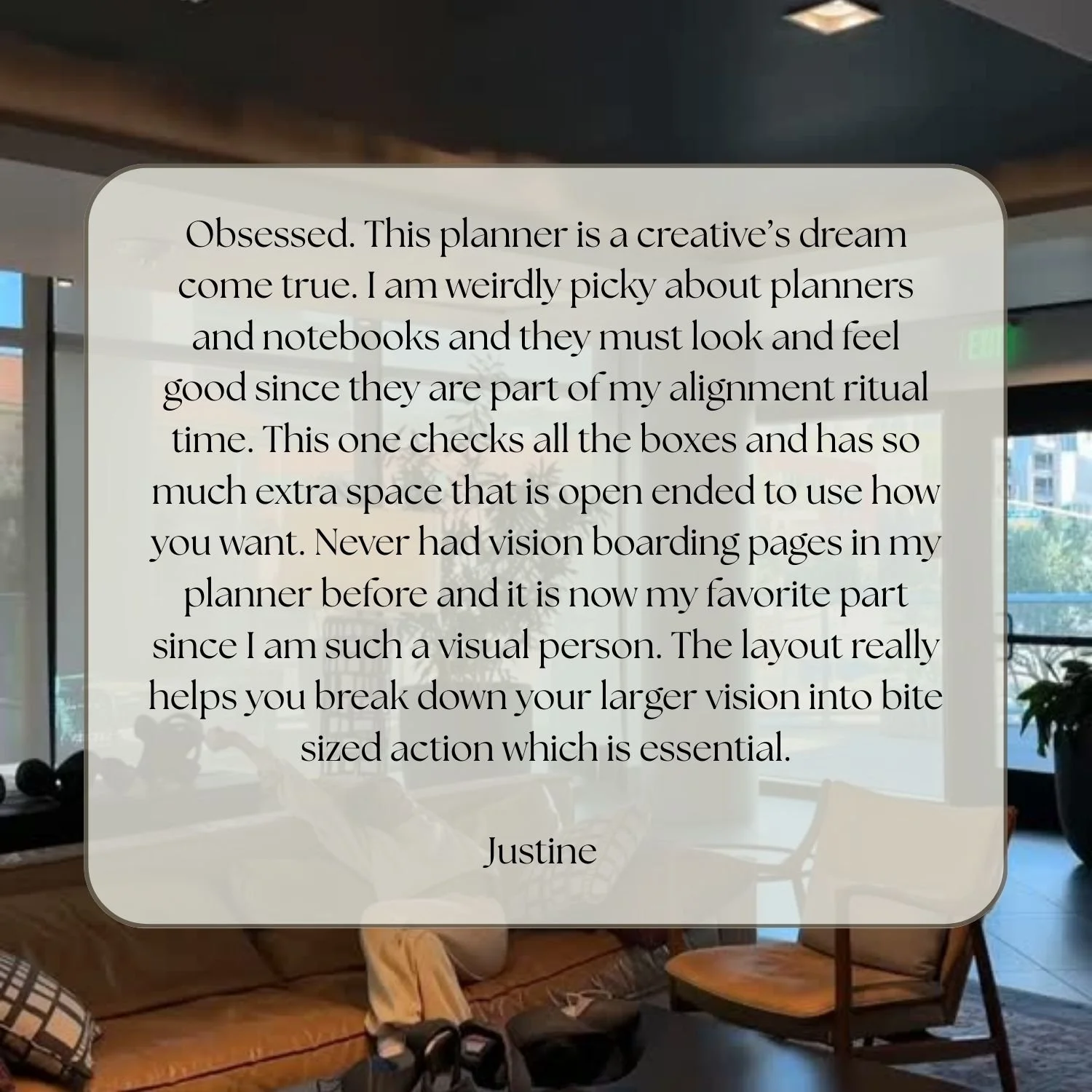 A transparent overlay with a review about a planner, text written by Justine, over a blurred indoor cafe scene with wooden furniture, chairs, a person seated, windows, and plants.