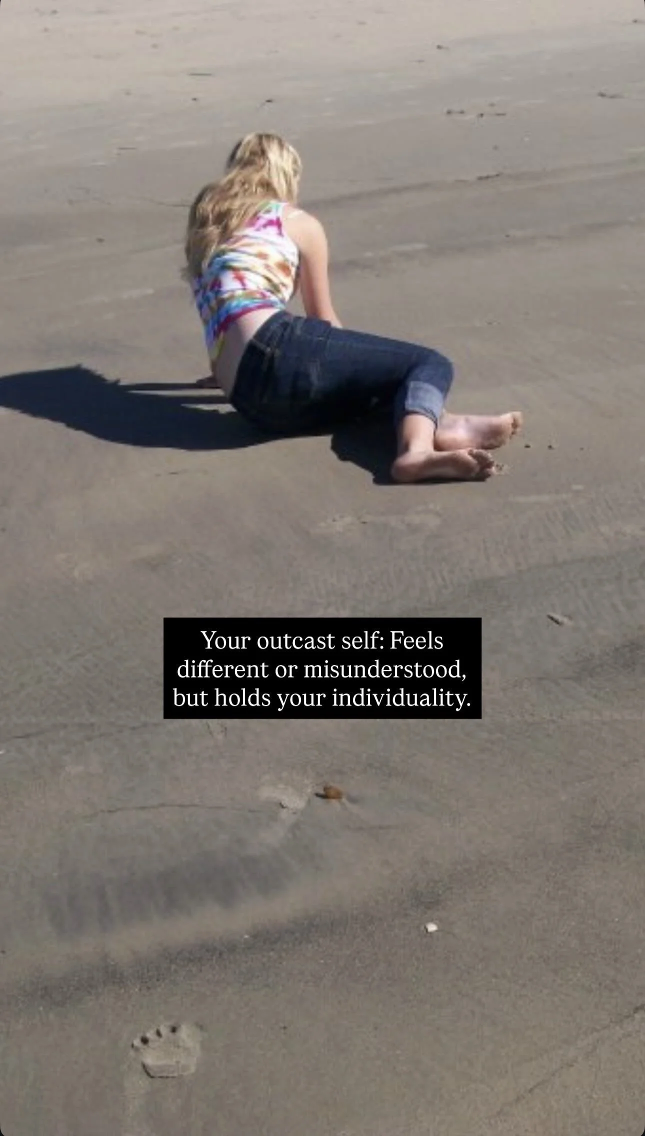 A person lying on their side on the sandy beach, with a text overlay that reads: "Your outcast self: Feels different or misunderstood, but holds your individuality."