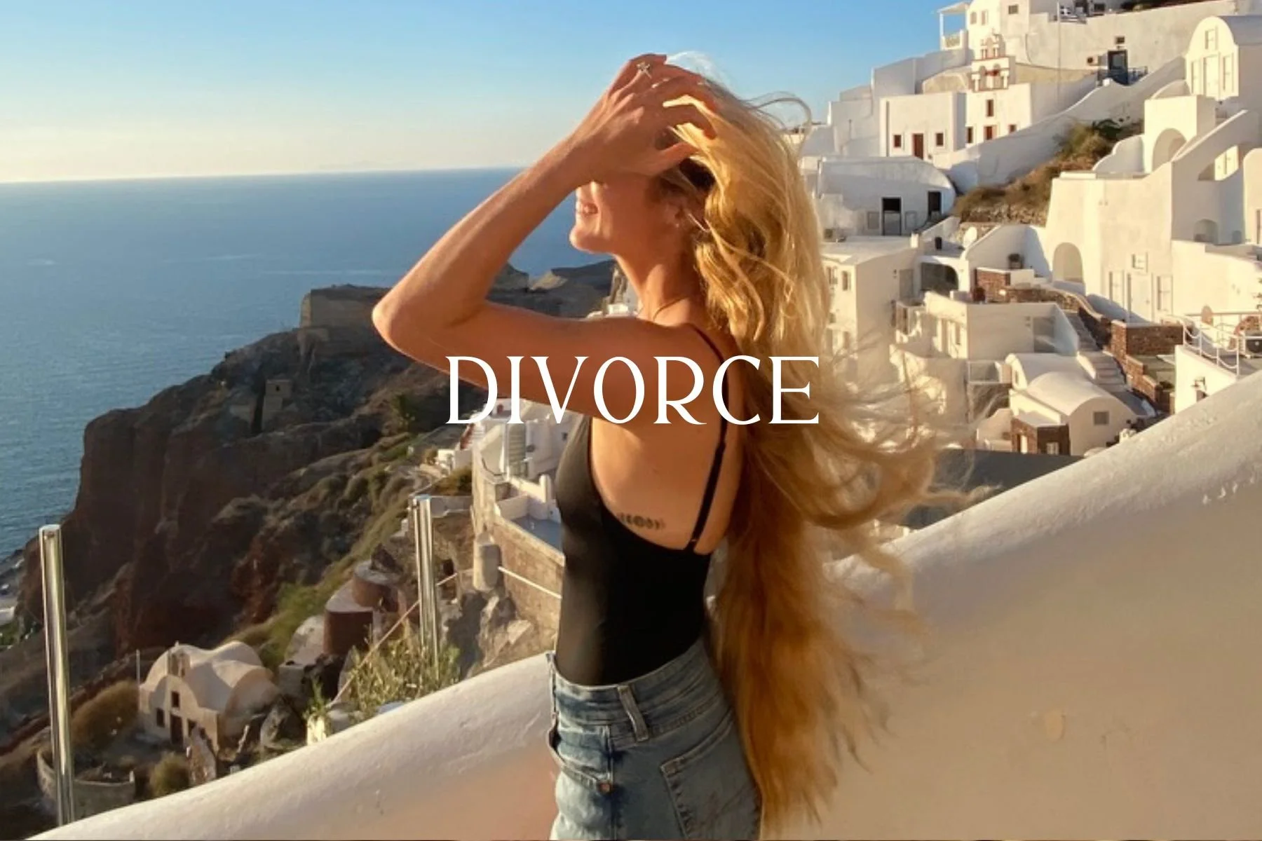 A woman with long red hair stands outdoors with a scenic coastal village in the background, and the word 'DIVORCE' overlayed on the image.