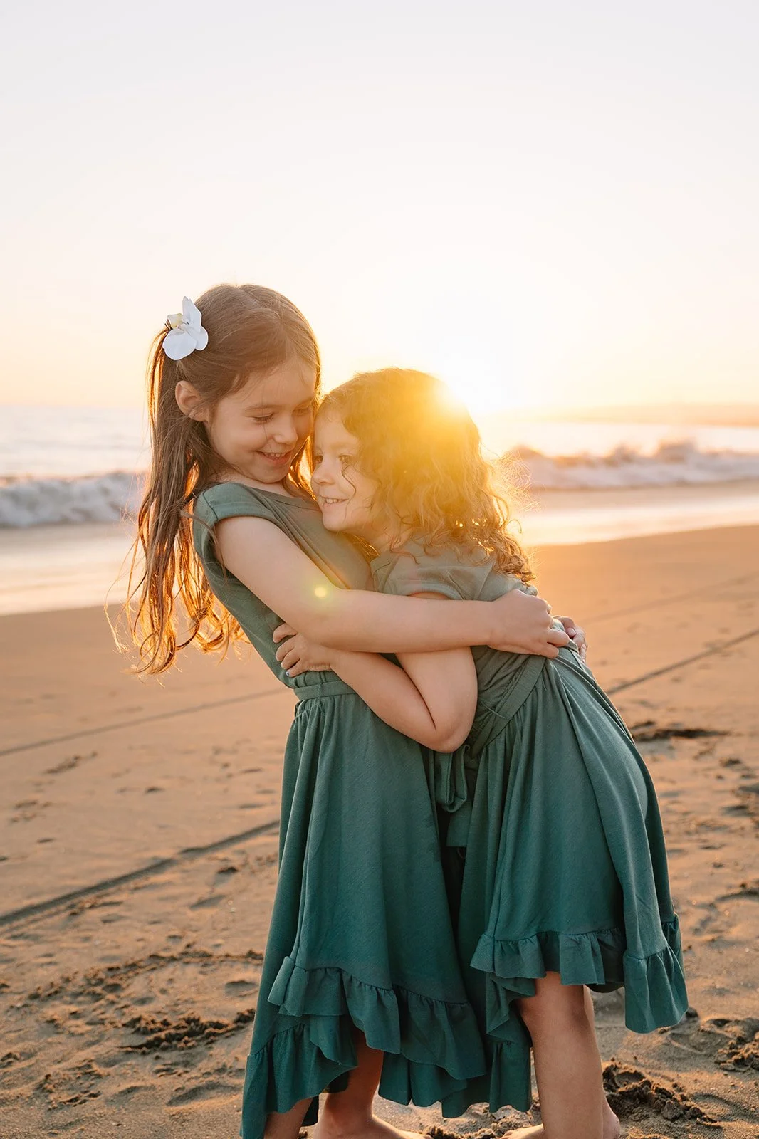 siblings hugging at the beach during golden hour