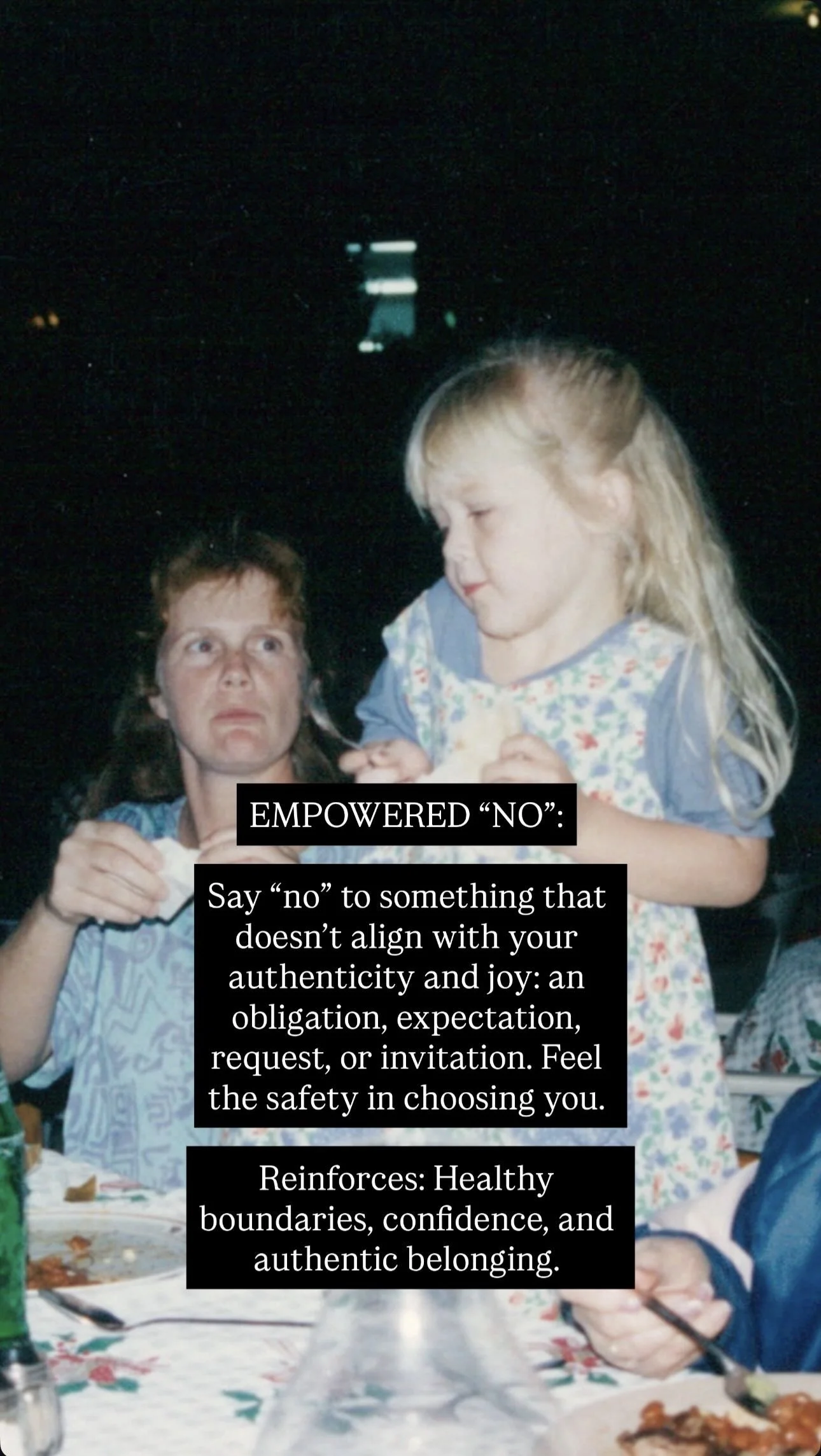 A woman with reddish-brown hair and a blue patterned shirt looks at a young blonde girl holding a piece of bread, both at a dinner table. The woman appears surprised or confused, and the scene is dark with some background lights.