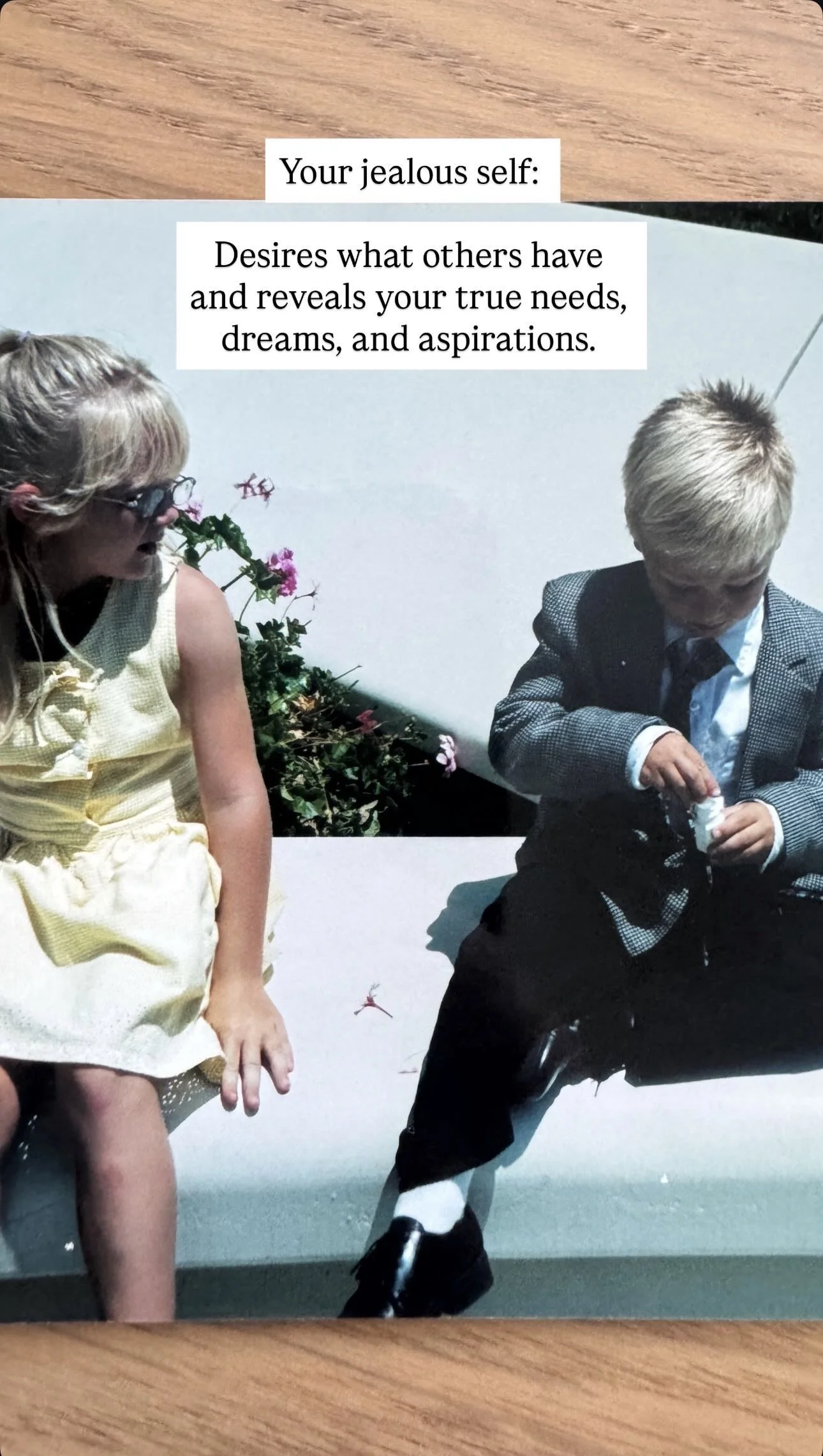 A girl in a yellow dress and glasses looking at a boy in a suit sitting on a bench, with a background of flowers. Text overlay: 'Your jealous self: Desires what others have and reveals your true needs, dreams, and aspirations.'
