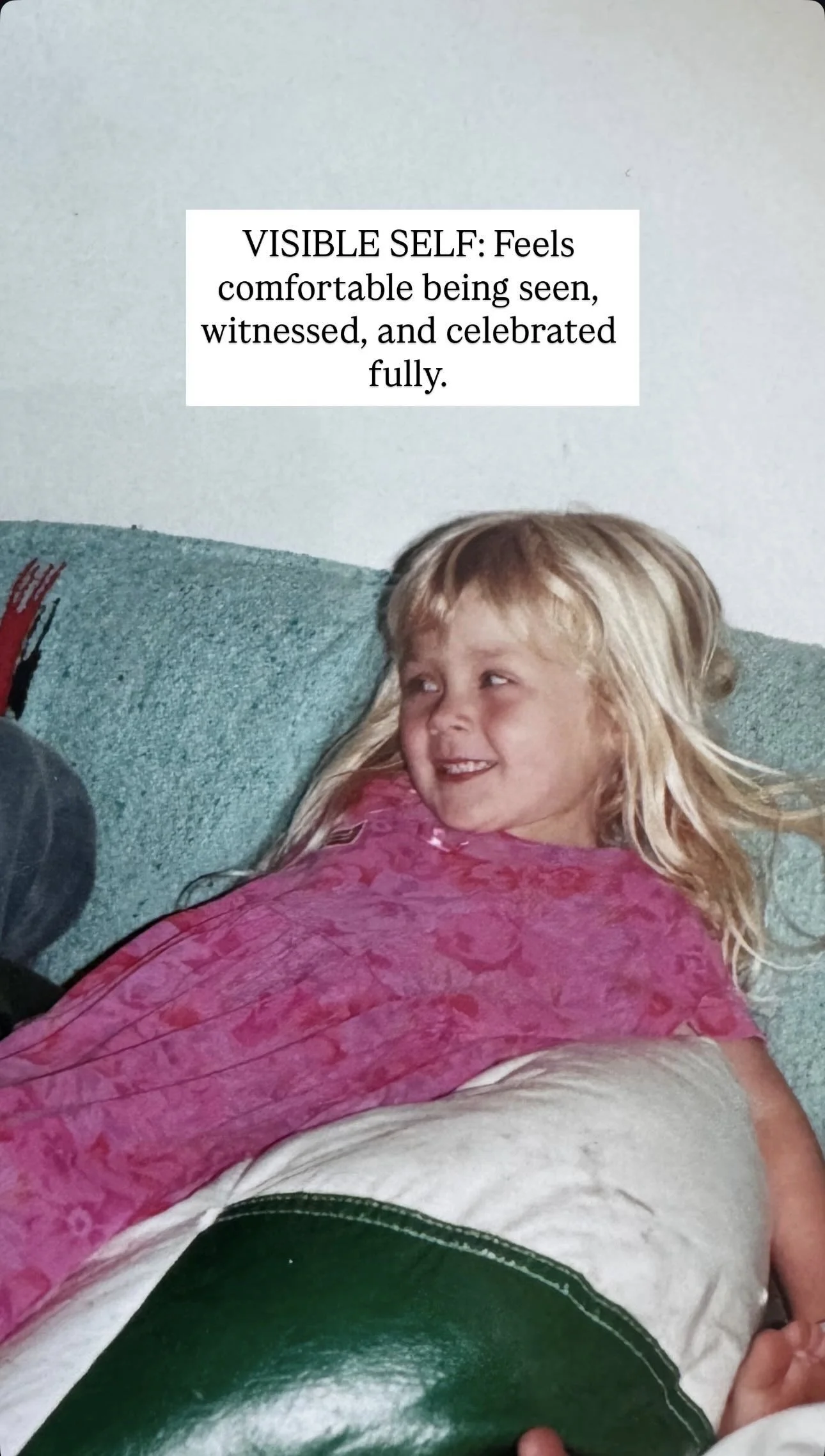 A young blonde girl smiling and lying on a couch, wearing a pink shirt, with a text overlay about feeling comfortable being seen.