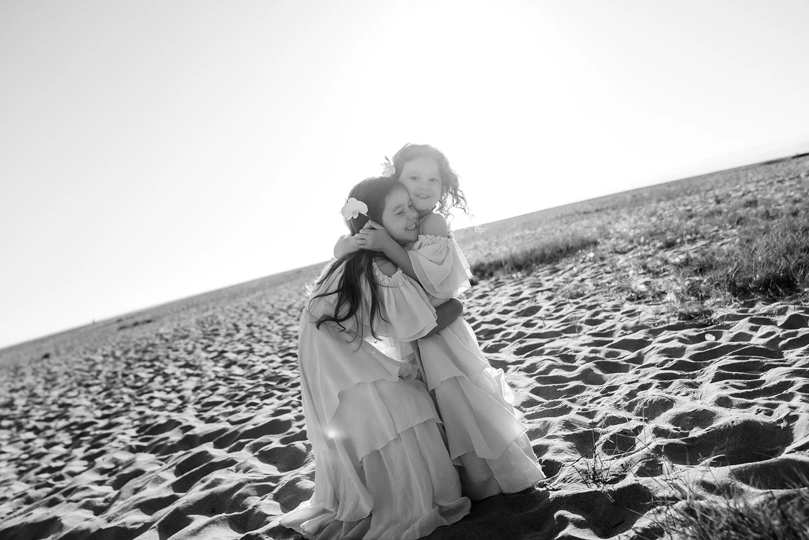 Two little girls hugging on the beach at Seascape