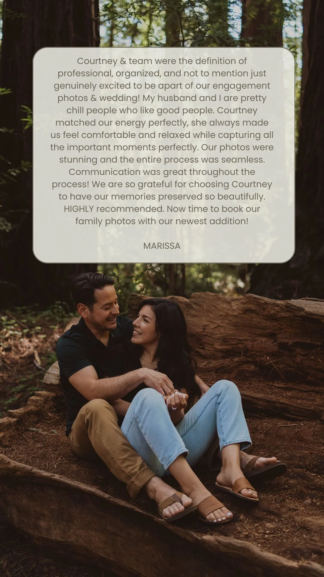 A couple sitting on the ground in a forest, smiling and sharing a moment together.