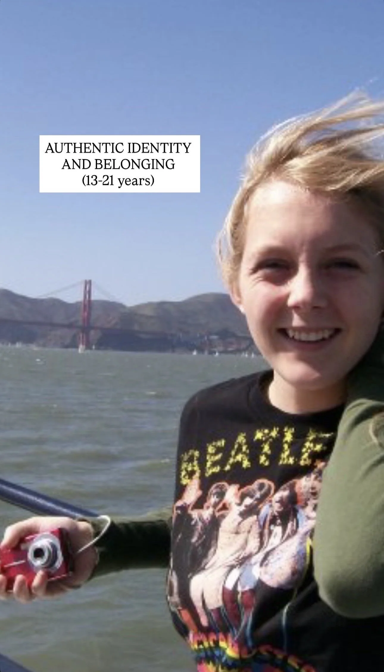 Young person smiling holding a camcorder in an outdoor setting with water and a bridge in the background. Text overlay reading 'Authentic Identity and Belonging (13-21 years)'.