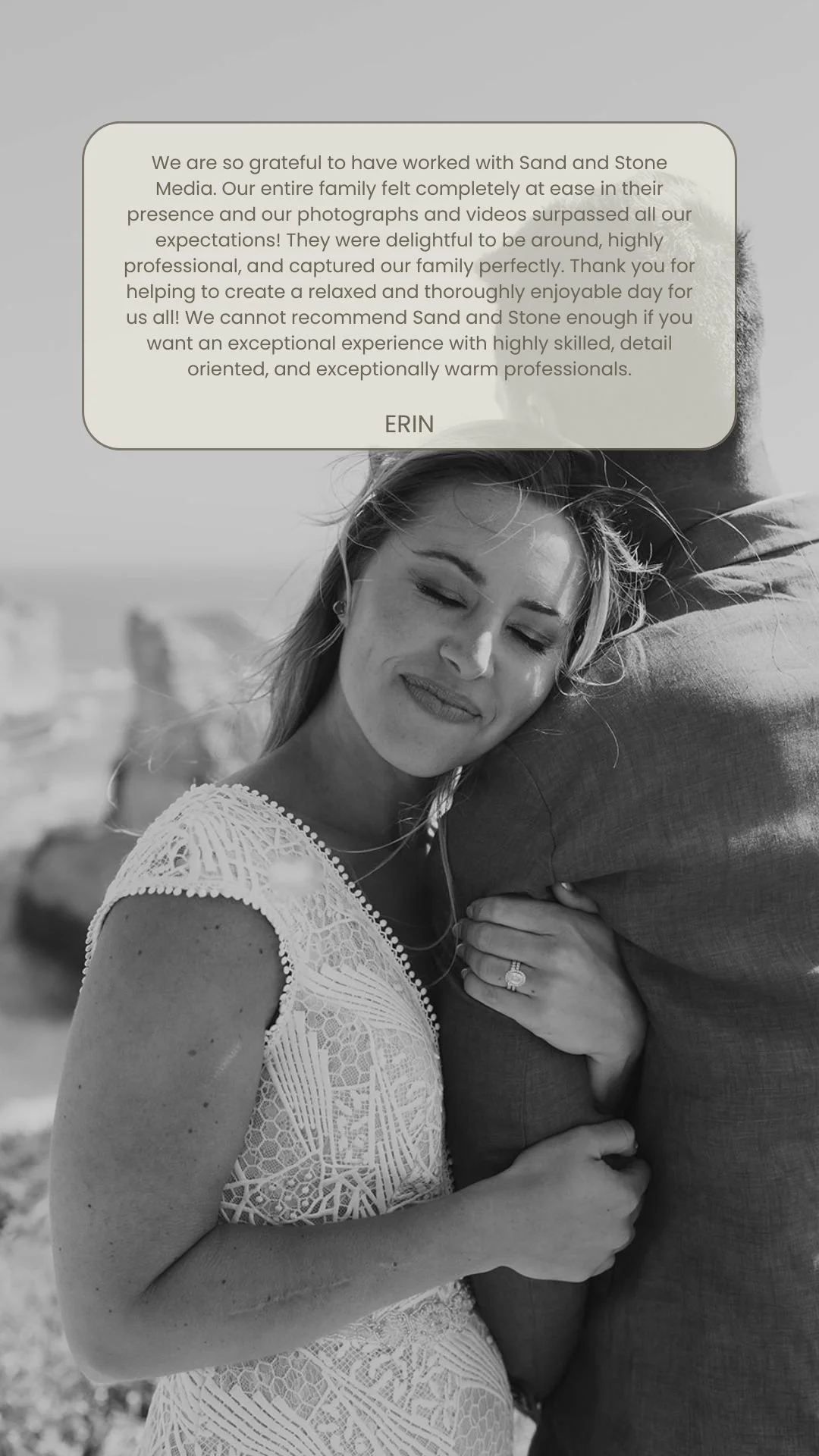 A black and white photo of a woman with closed eyes, smiling, wearing a lace dress, holding someone close, with a scenic outdoor background.