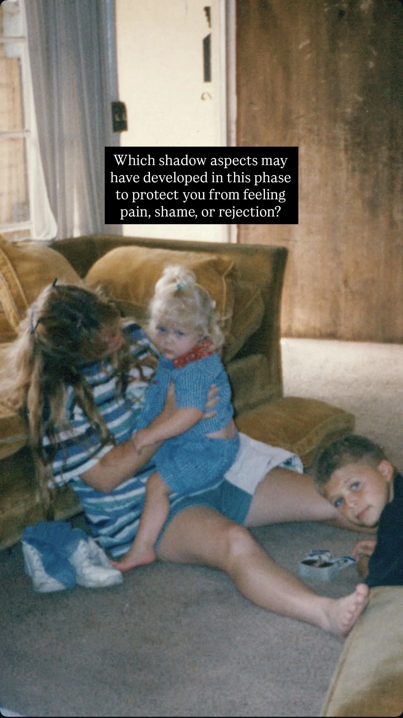Children playing and hugging inside a living room with a couch, carpet, and wooden wall.