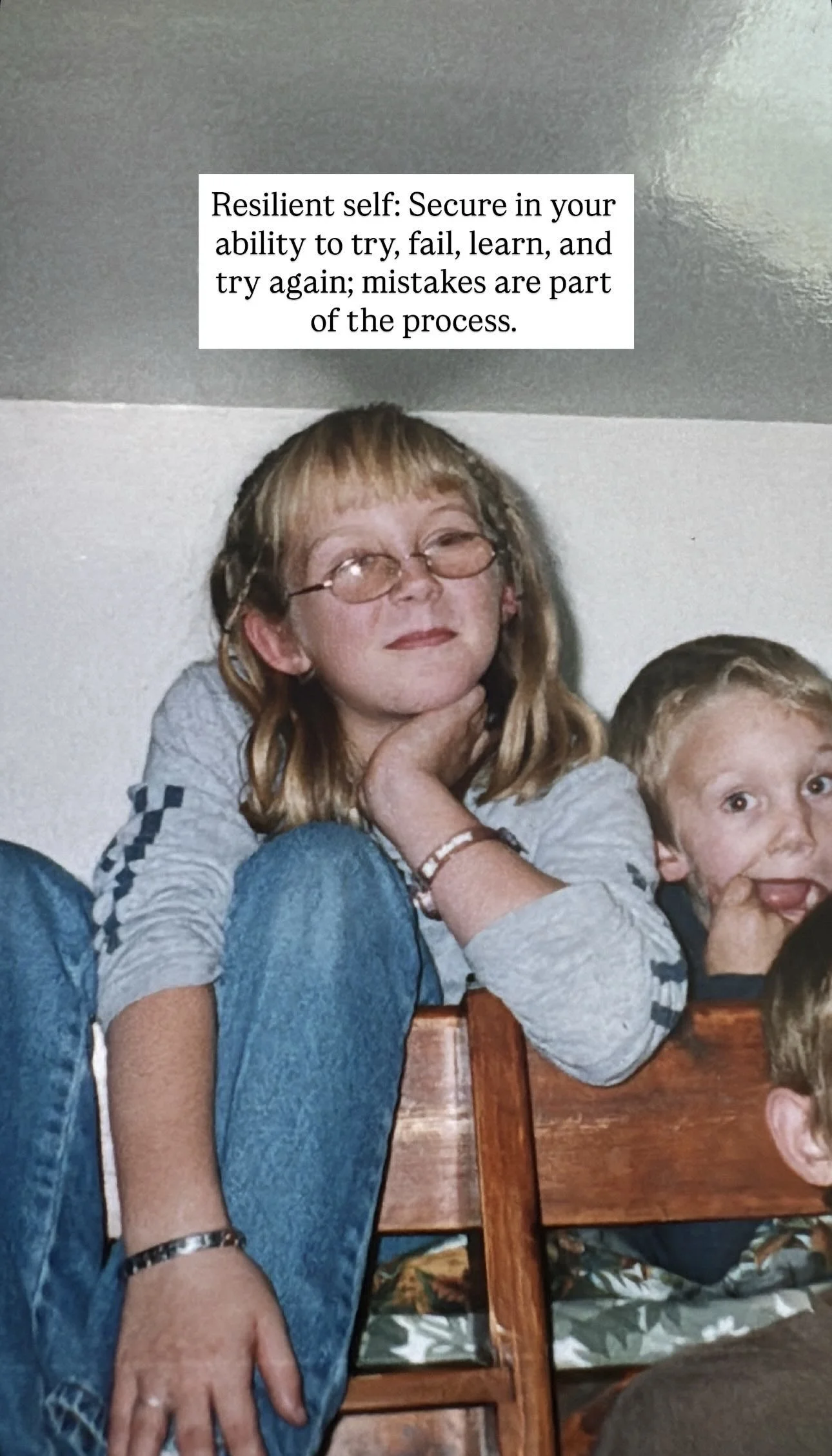 A girl with glasses and long blonde hair sitting on a wooden chair, resting her chin on her hand, with a boy beside her smiling. A quote about being resilient in learning is displayed at the top.