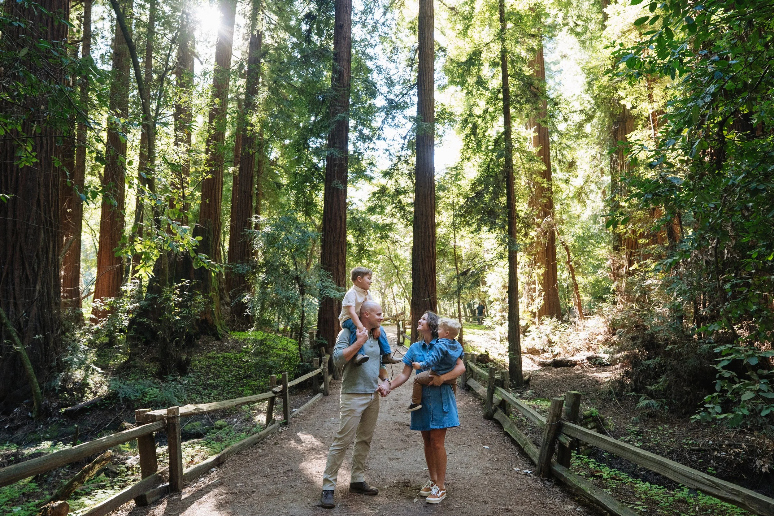 Family of four smiling at Henry Cowell Redwood State Park for family photos
