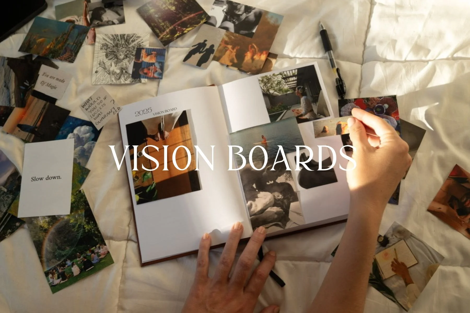 A person is creating vision boards on a bed with a white sheet, surrounded by cutout photos, cards, and a pen. The open book in the center has the caption 'VISION BOARDS' and 2025, with images of nature, relaxation, and inspiration.