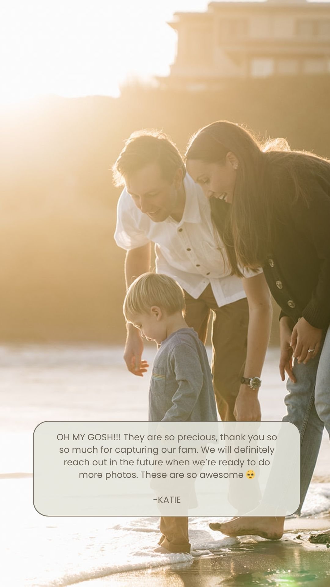 A family of three, a man, a woman, and a young boy, standing on the edge of the water at the beach during sunset, smiling and looking at the water.