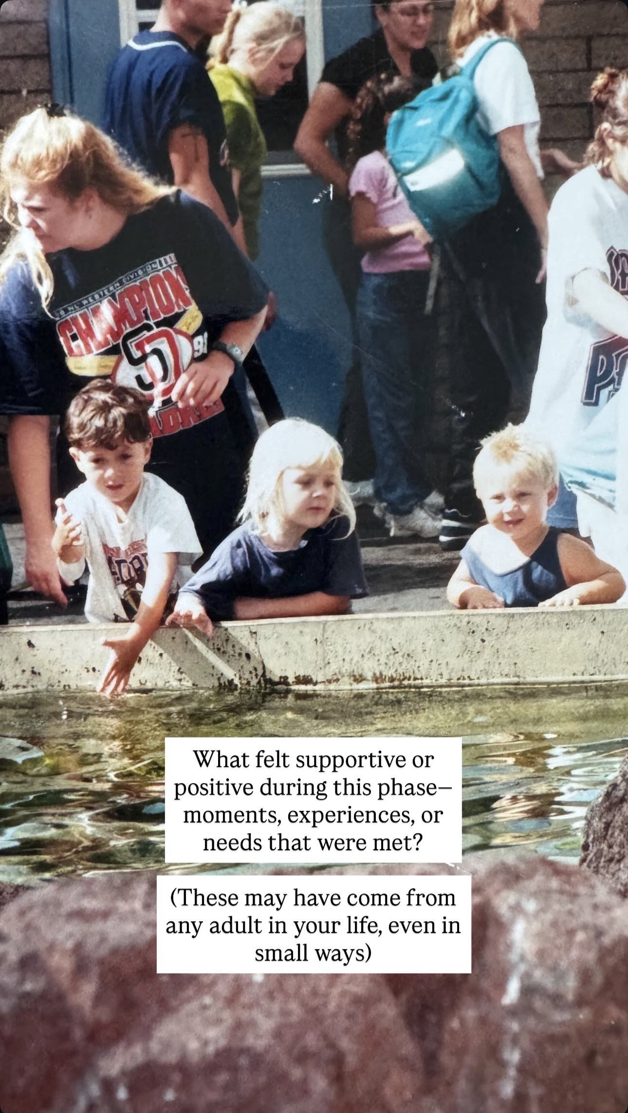 Children leaning over a water feature, with several adults standing behind them, watching and engaging in an outdoor activity.