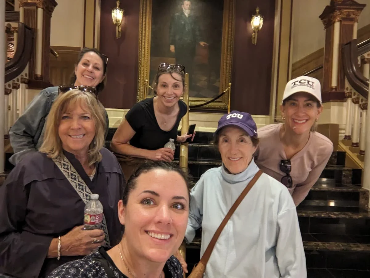 Walking tour guests pose with tour guide in front of Jesse Driskill portrait painting.