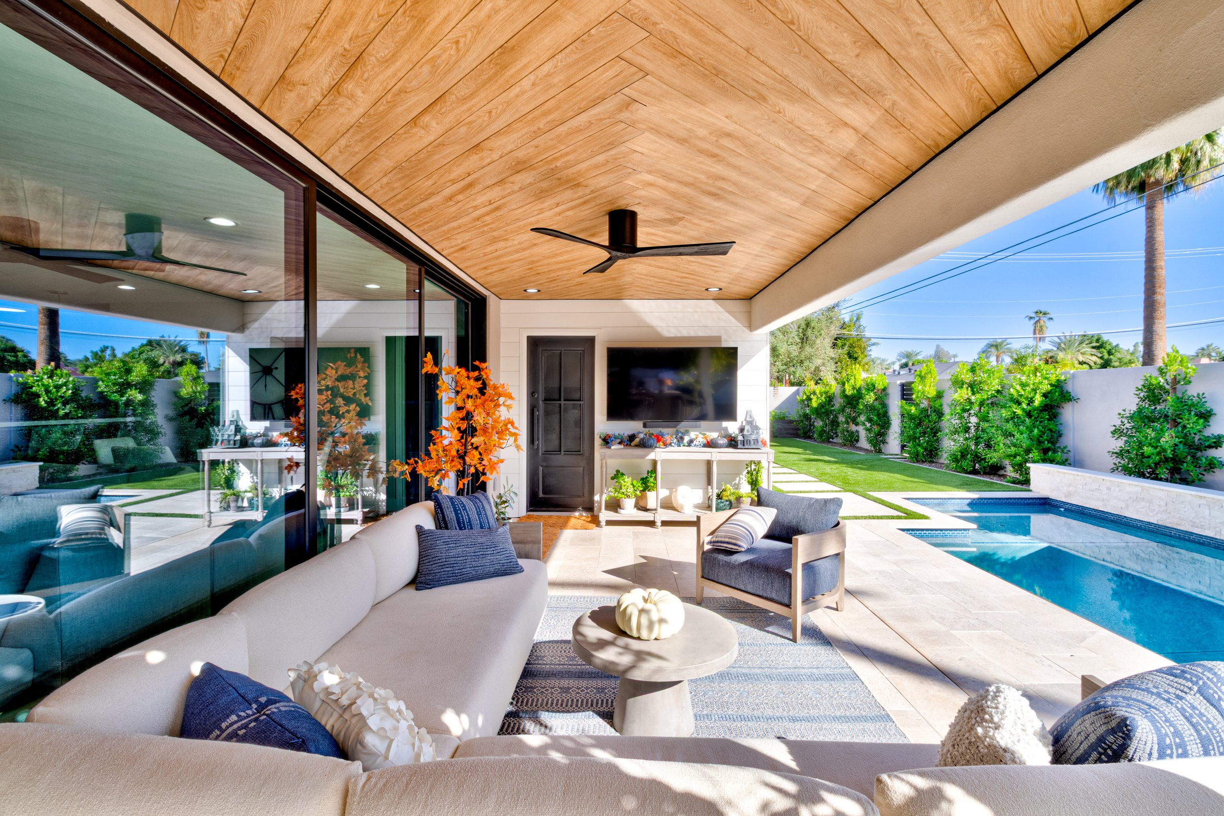 Covered patio at a Phoenix home with a custom wood-plank ceiling and large sliding glass doors overlooking a backyard pool.