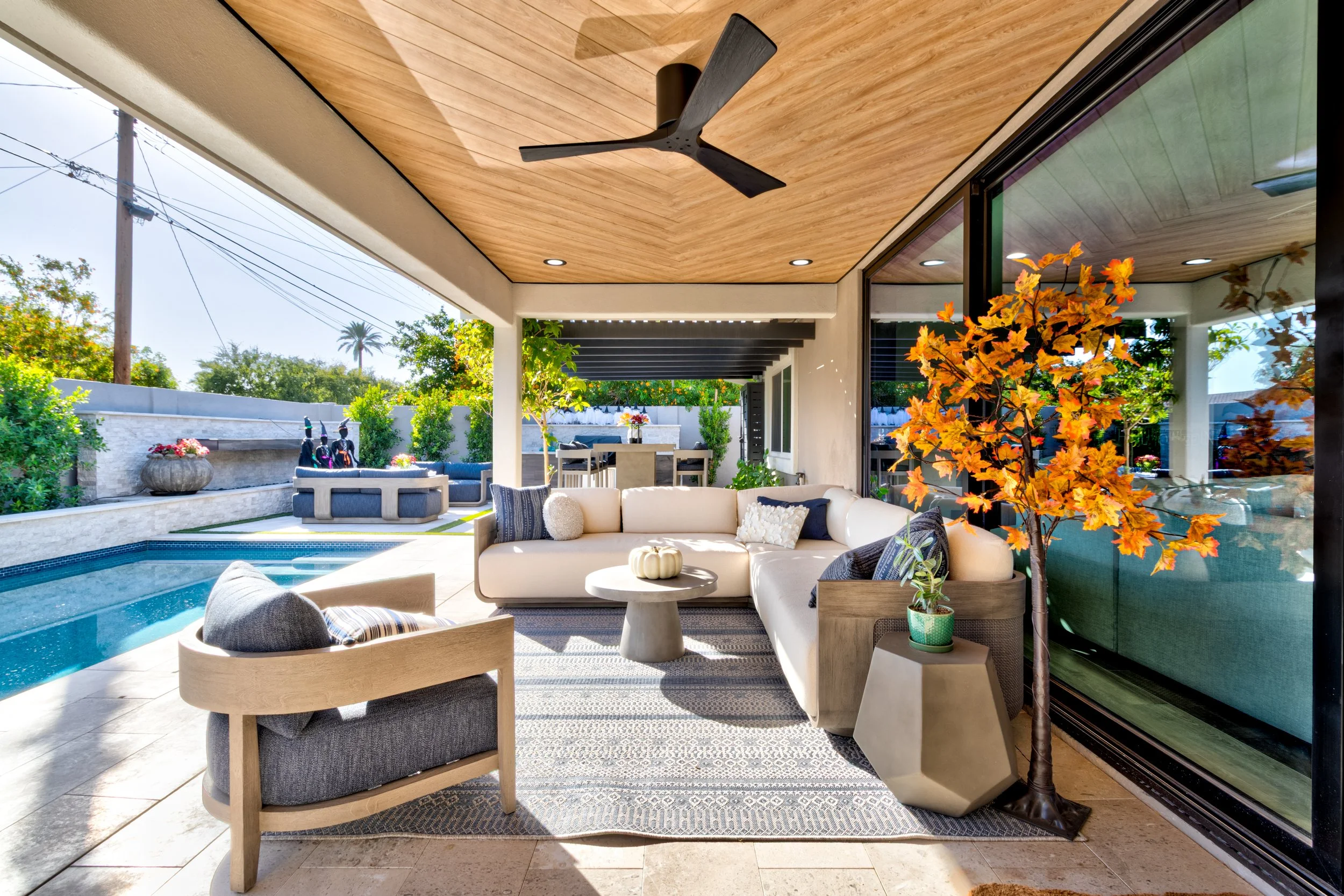 Covered patio at a Phoenix home with a custom wood ceiling, ceiling fan, sliding glass doors, and outdoor seating.