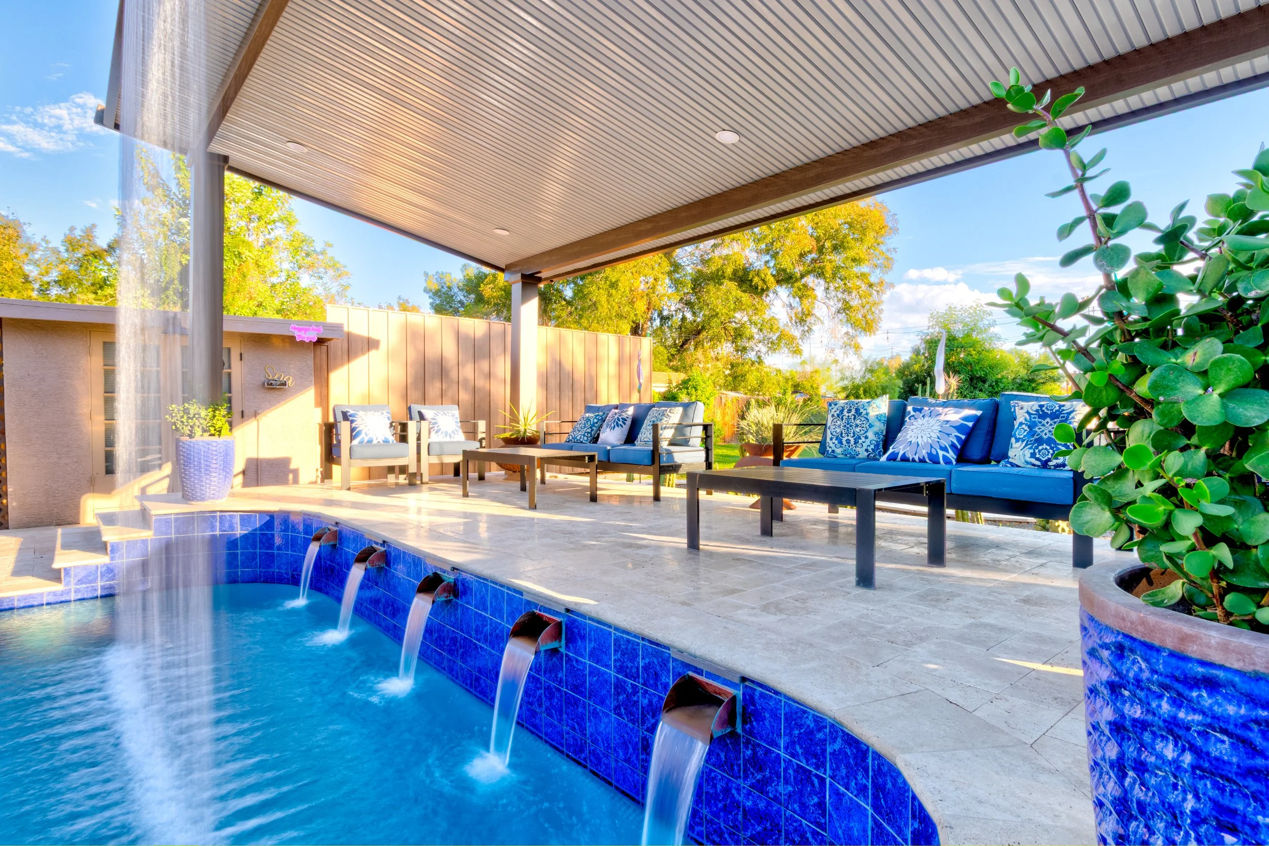 Tempe backyard pool with blue tile accents, waterfall spouts, and a curtain waterfall beside a poolside ramada.