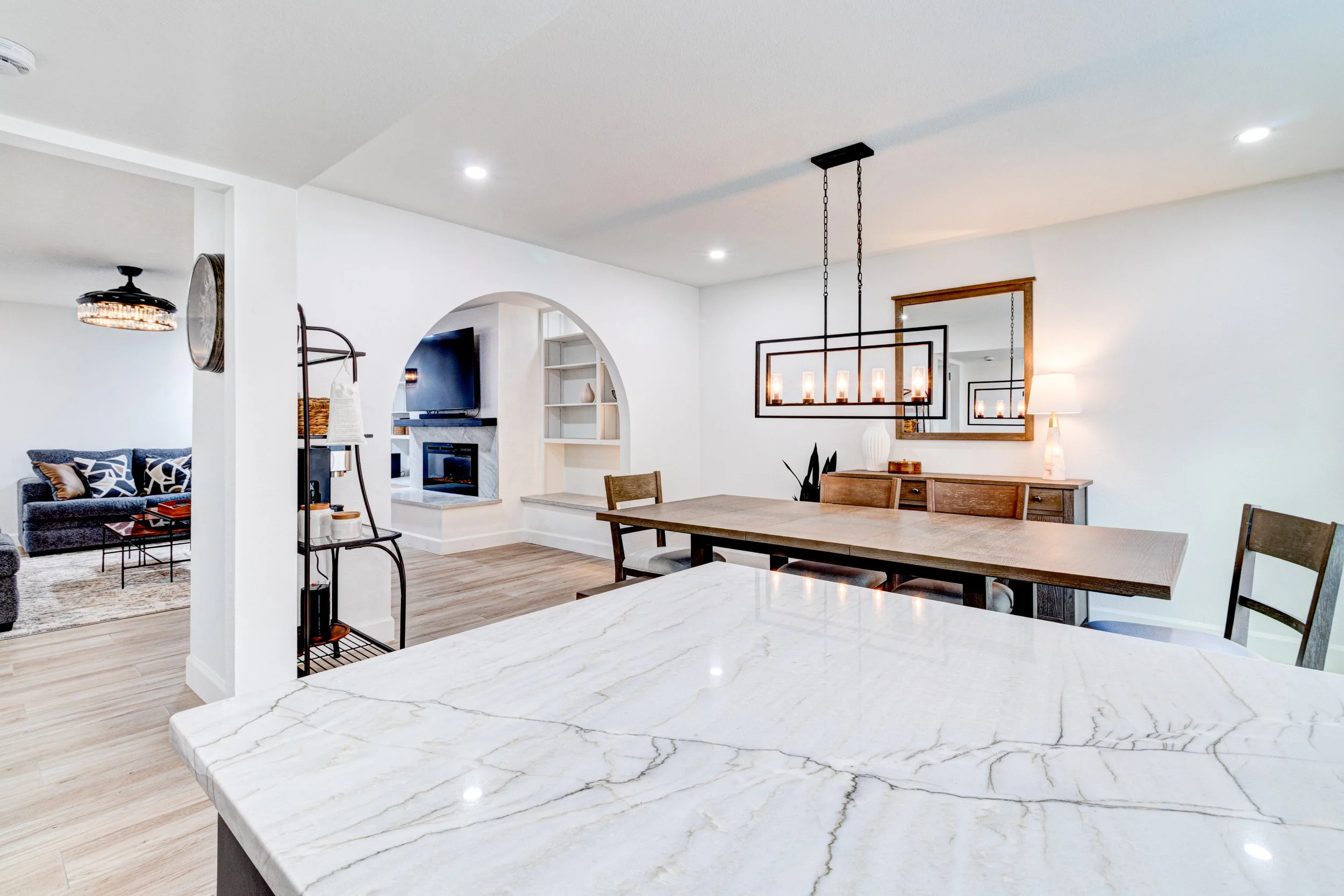 Kitchen in Phoenix’s Arcadia area with white veined countertops, pendant lighting, and an adjoining dining area.