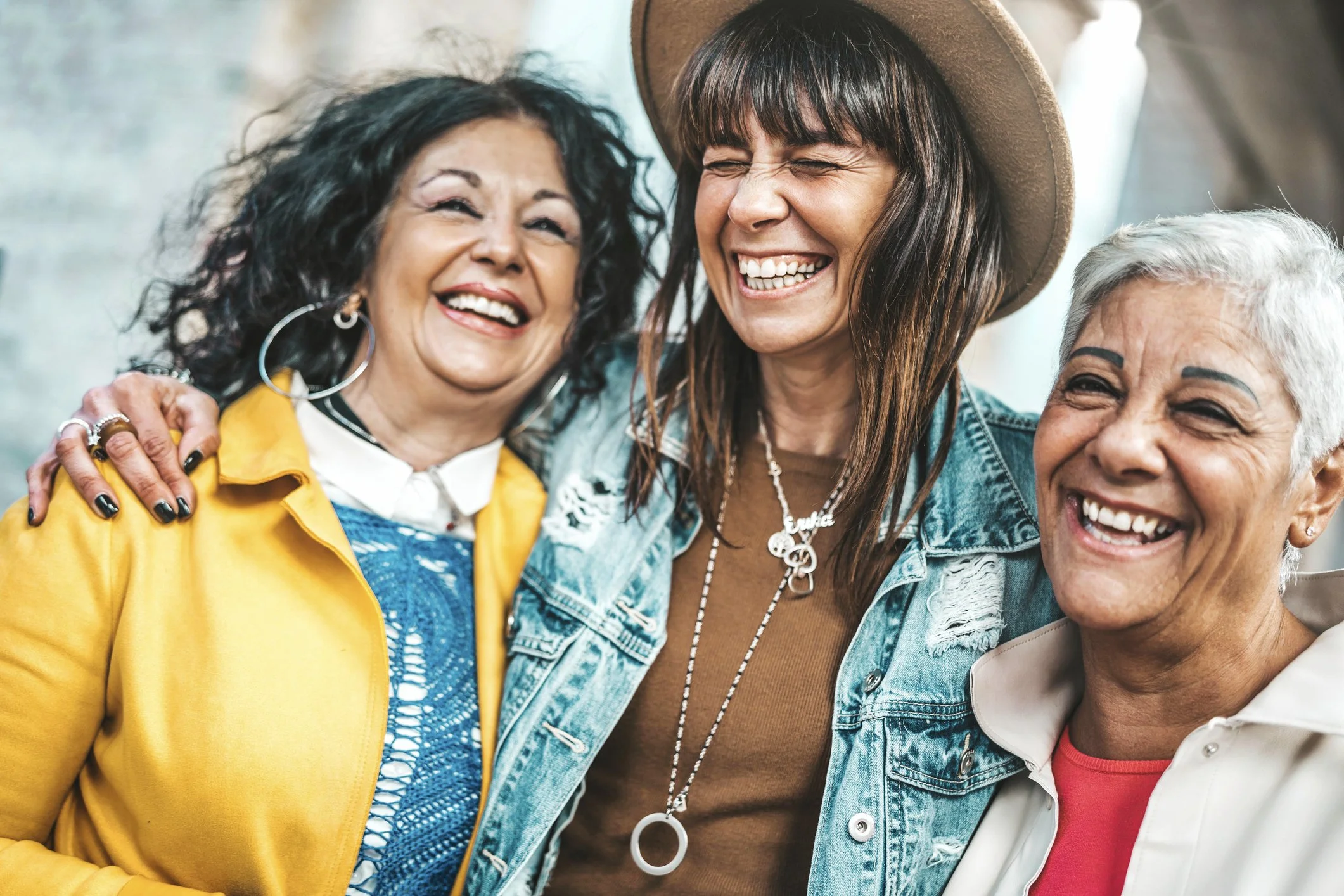 three women, each from a different generation, are holding each other and laughing.