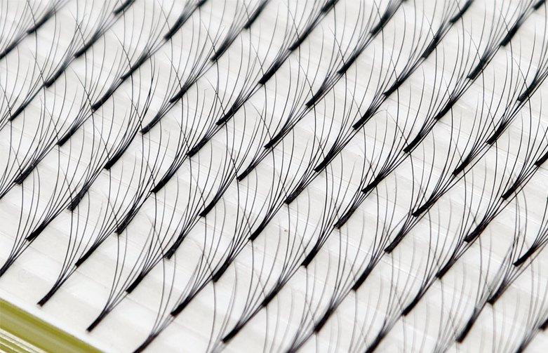 Close-up of multiple eyelashes arranged in rows on an eyelash extension tray.