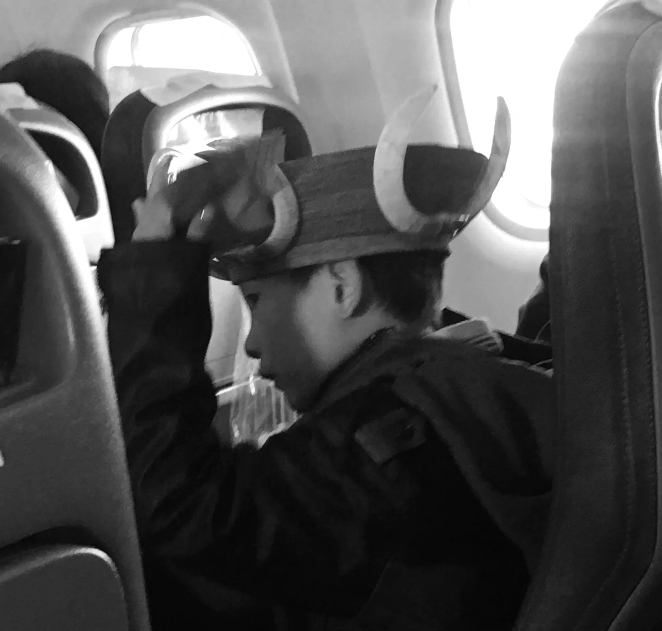Boy on plane wearing bamboo and tusk hat.