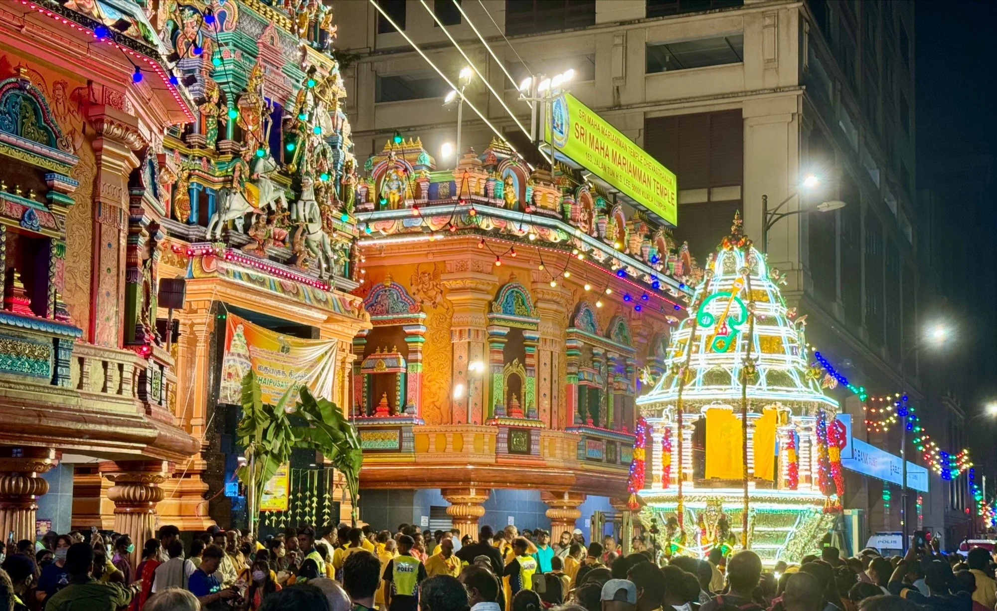 The brightly-lit chariot leaving the temple through the crowds.
