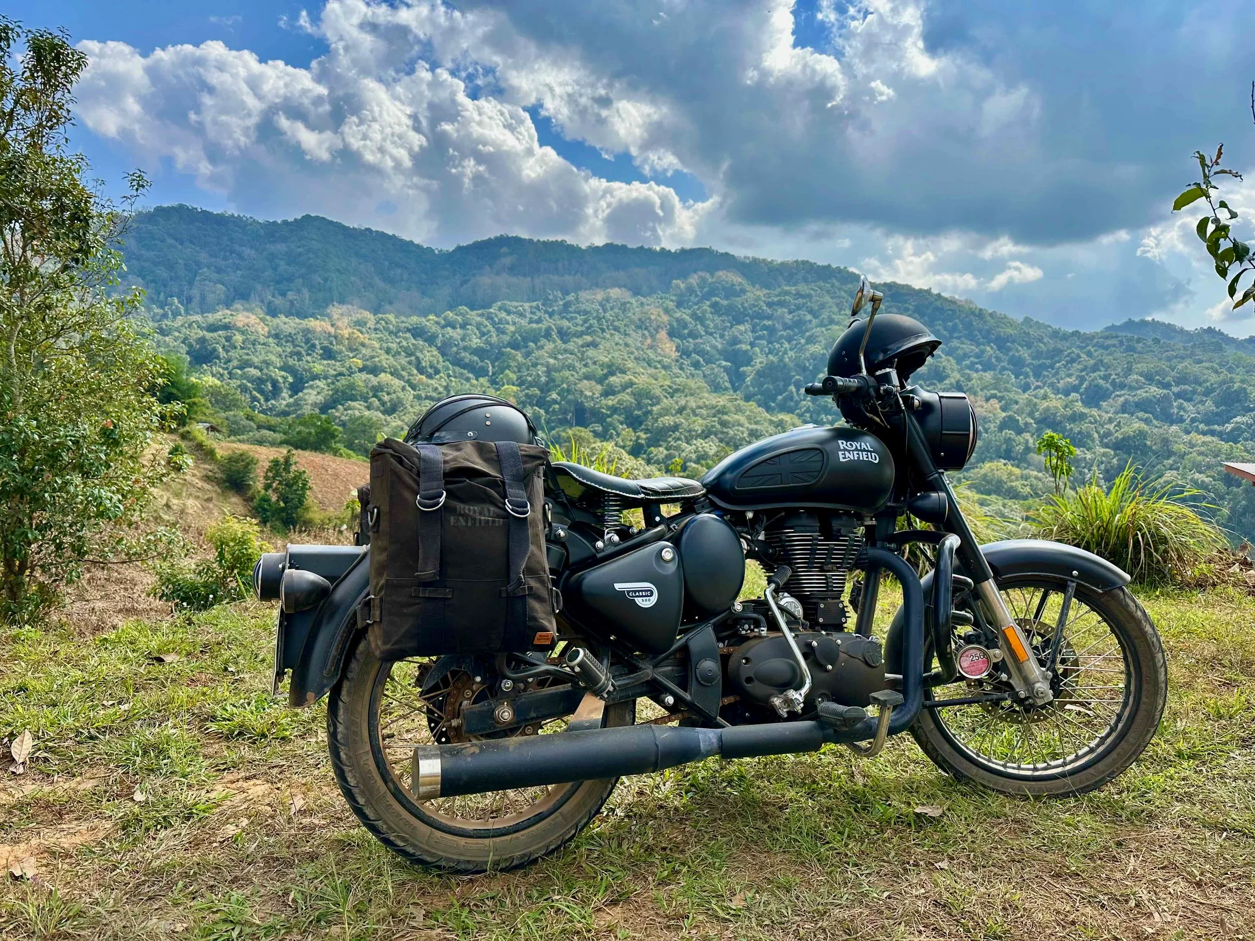 The author's Royal Enfield motorcycle parked up in front of mountains and jungle.