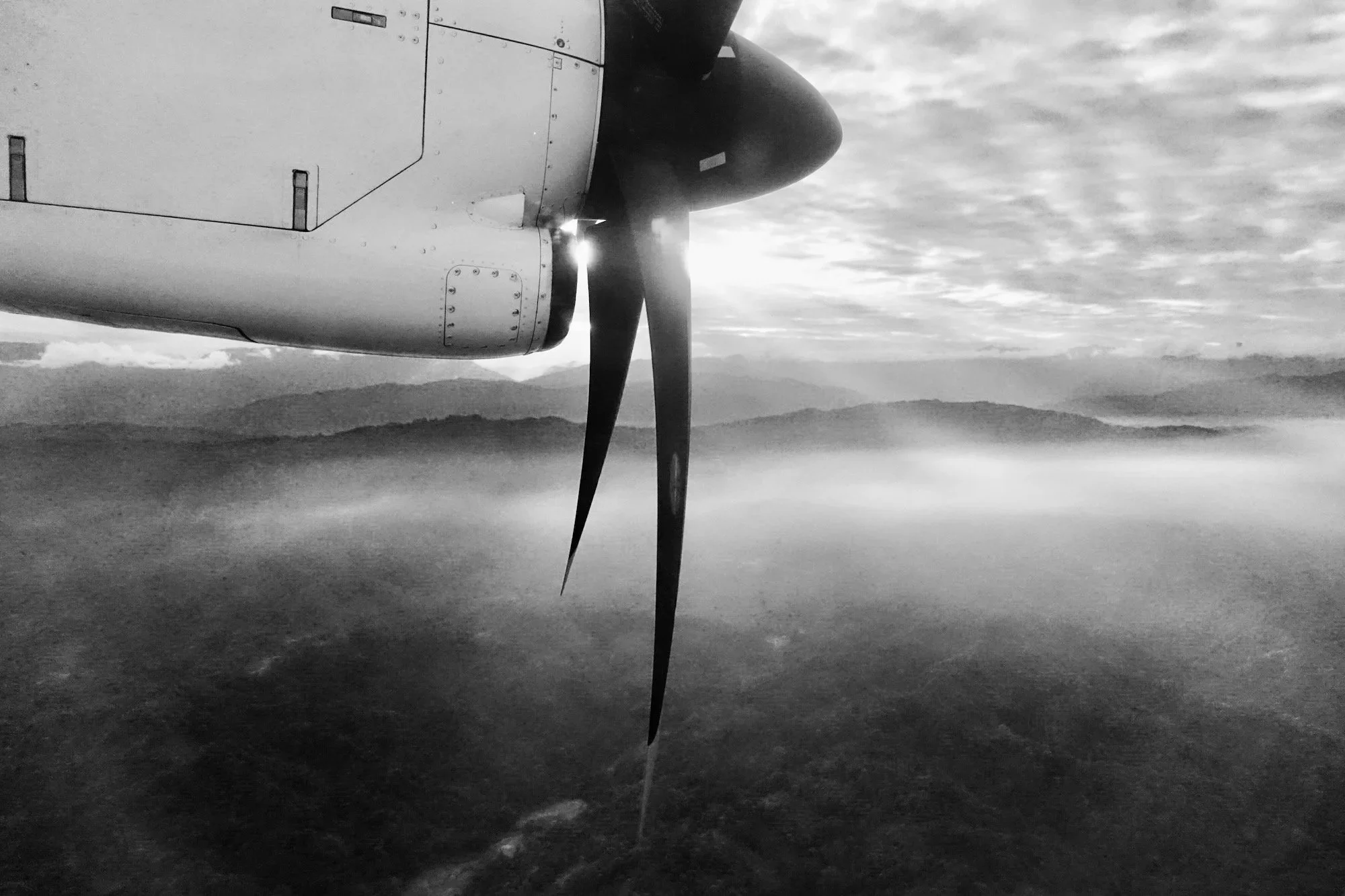 View from the plane window of the propeller and the vast jungle-covered hills below.