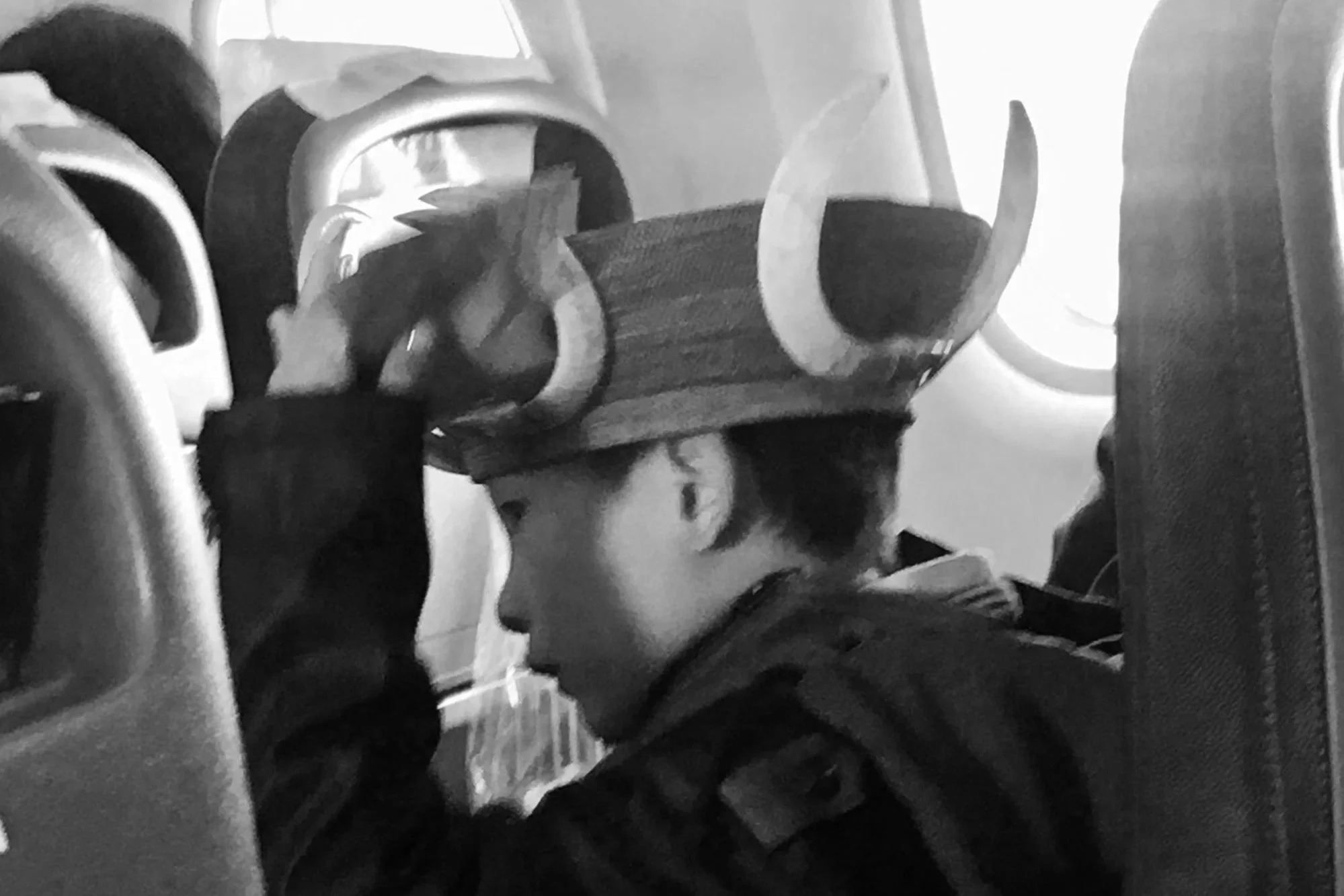 Boy on the plane wearing a hat made of bamboo and animal tusks.