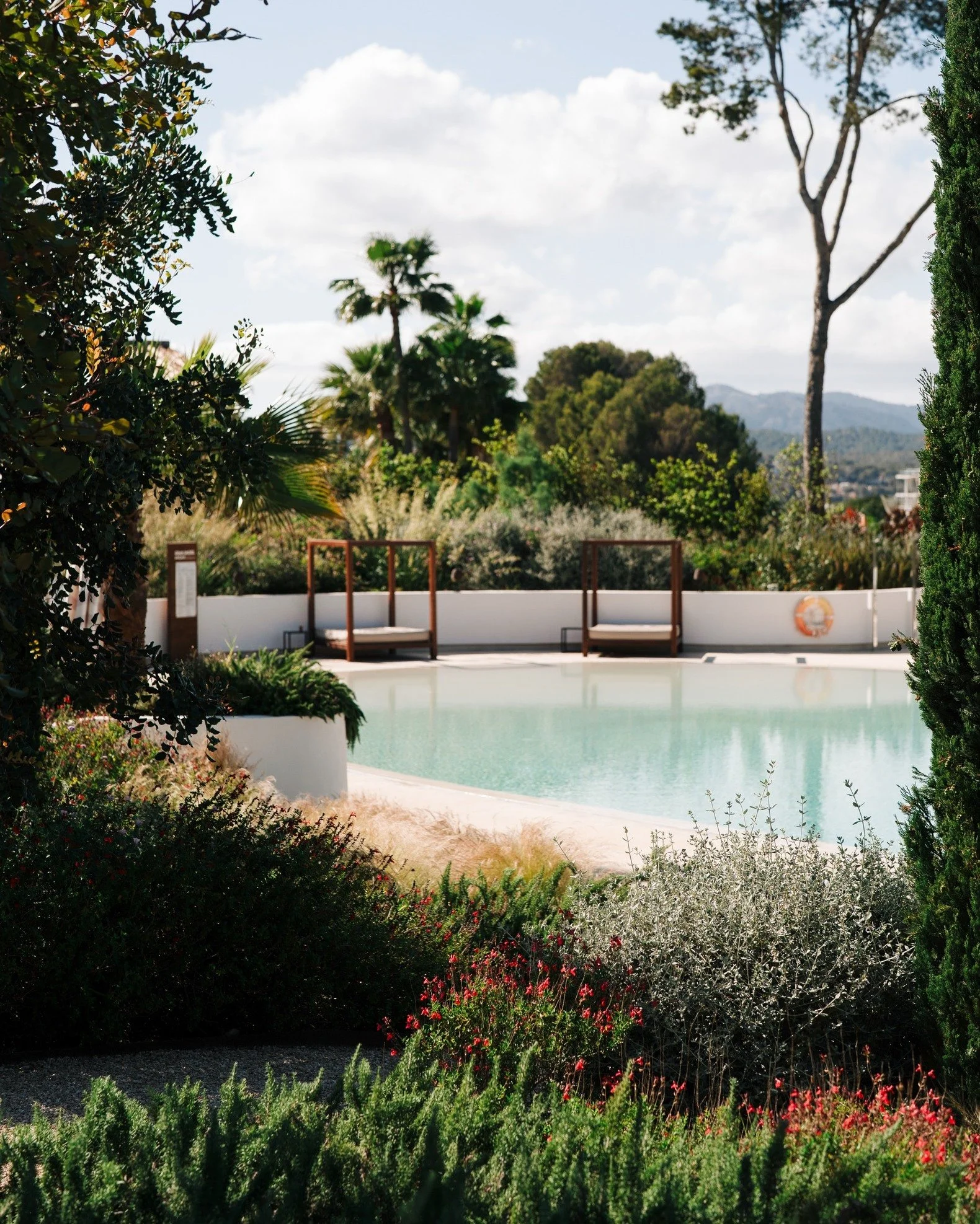 Soft light. Still water. Layers of green. 🍃

The way this resort blends architecture into nature is something special&mdash;this view through the garden toward one of @kimptonayslamallorca&rsquo;s tranquil outdoor pools felt like a moment of pure ba