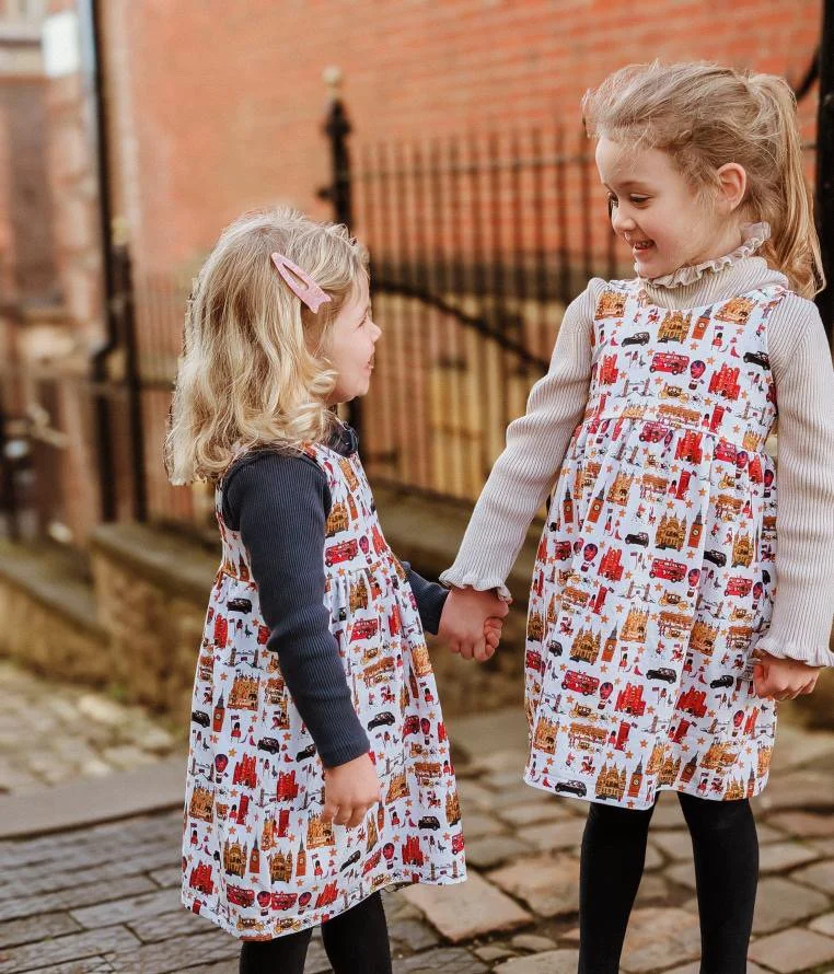 Two little British girls wearing London style organic matching dresses