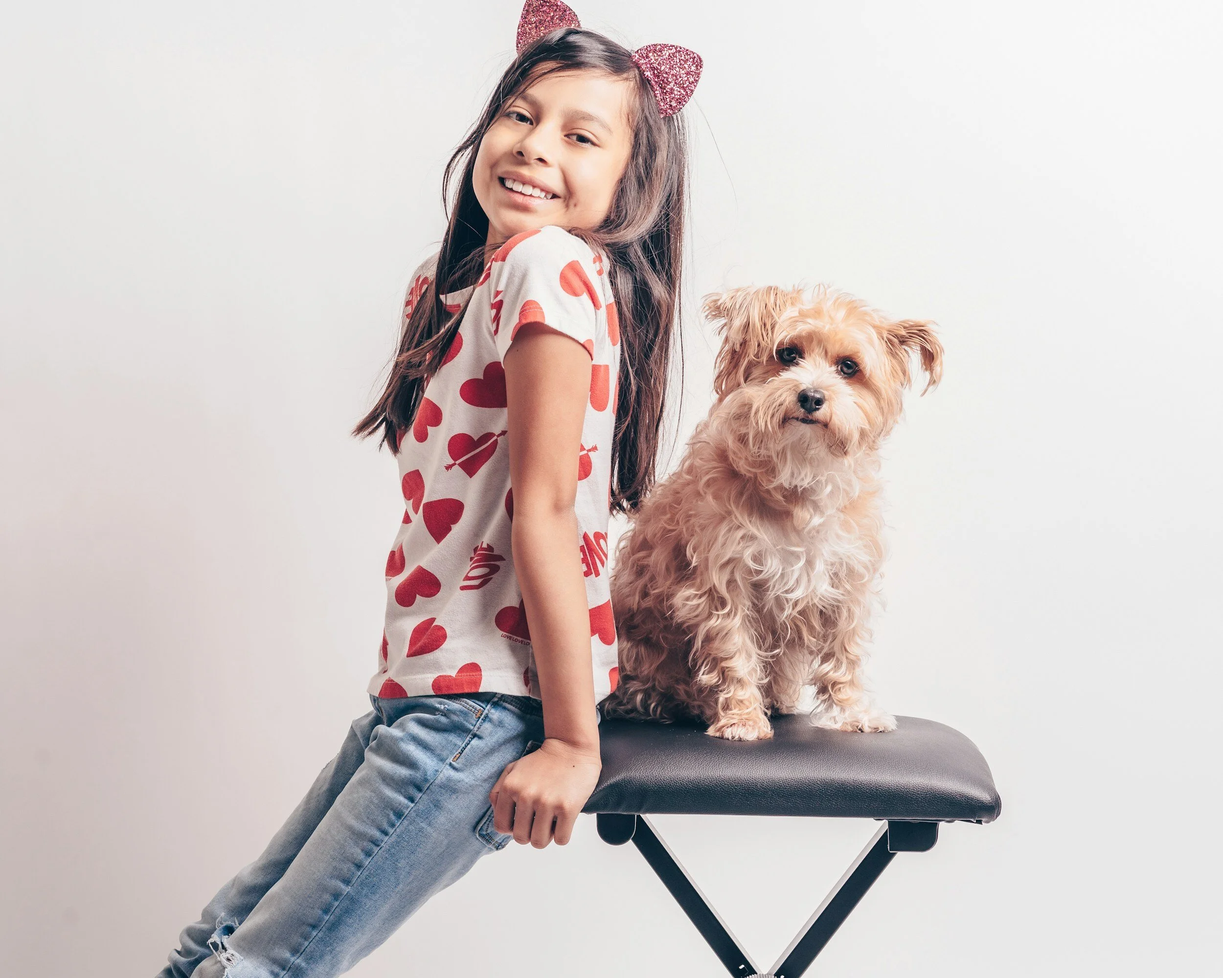 young girl takes a picture next to her dog on a chair