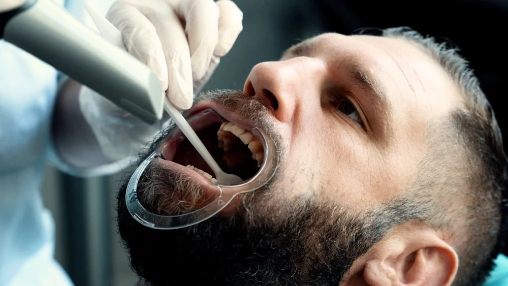 Gros plan d’un patient lors d’un soin dentaire filmé pour une vidéo de présentation.
