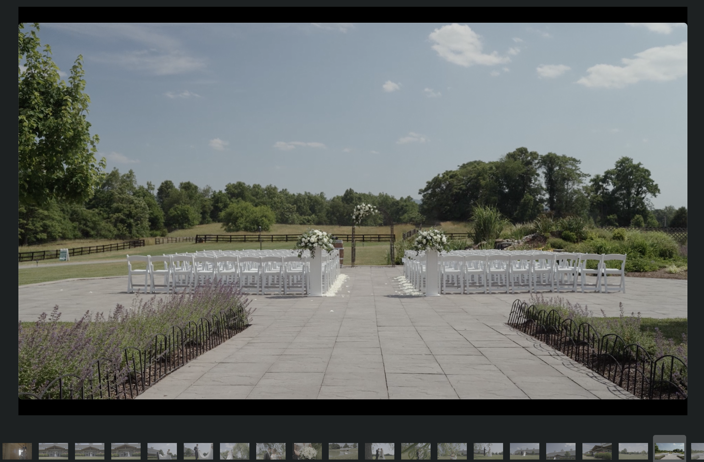 Outdoor wedding ceremony setup with white chairs and floral decorations in a garden setting.