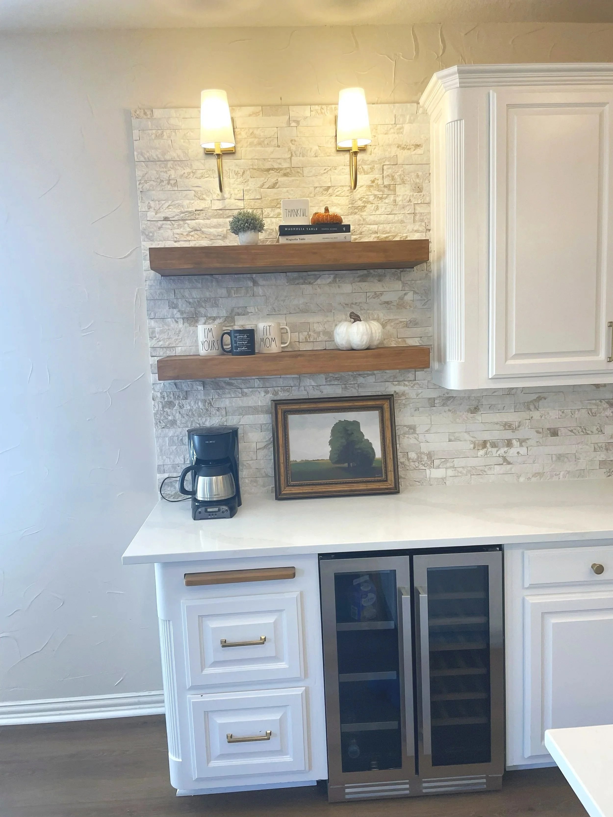 Custom kitchen coffee bar remodel with floating wood shelves, stone backsplash, brass sconces, and built in wine refridgerator.