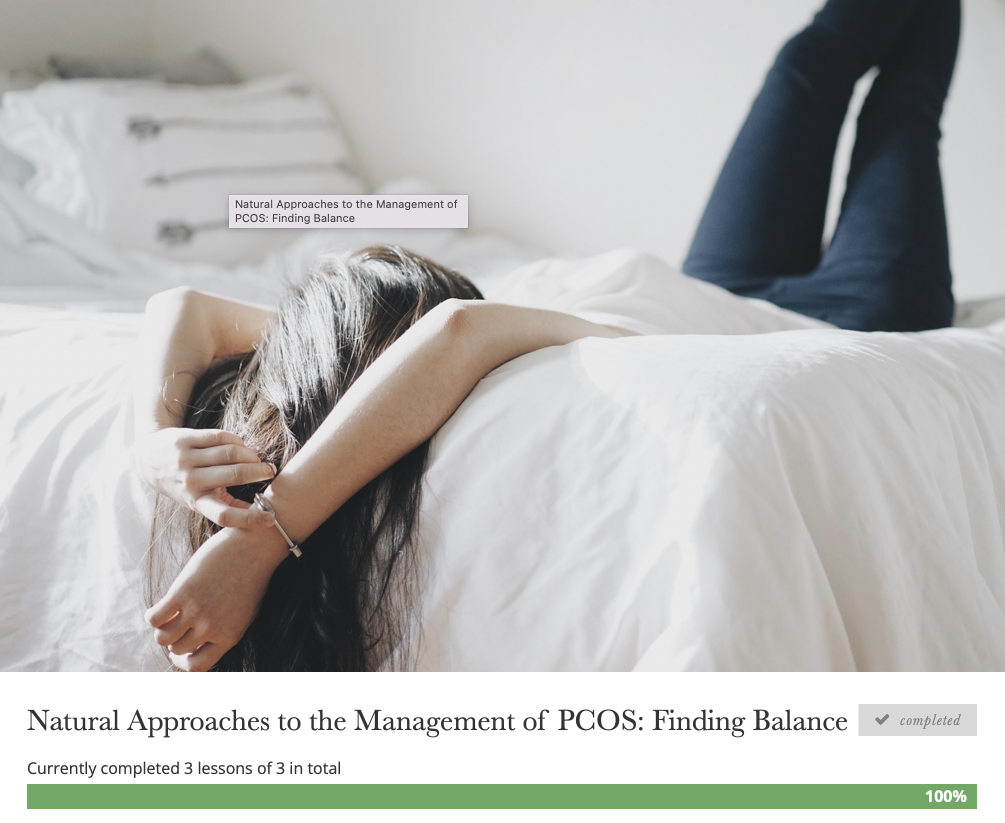 A woman lying face down on a bed with her arms wrapped around her head. She has long brown hair and is wearing a black bracelet and dark jeans. The bed has white bedding, and sunlight is illuminating the scene. There is a text overlay on the image th