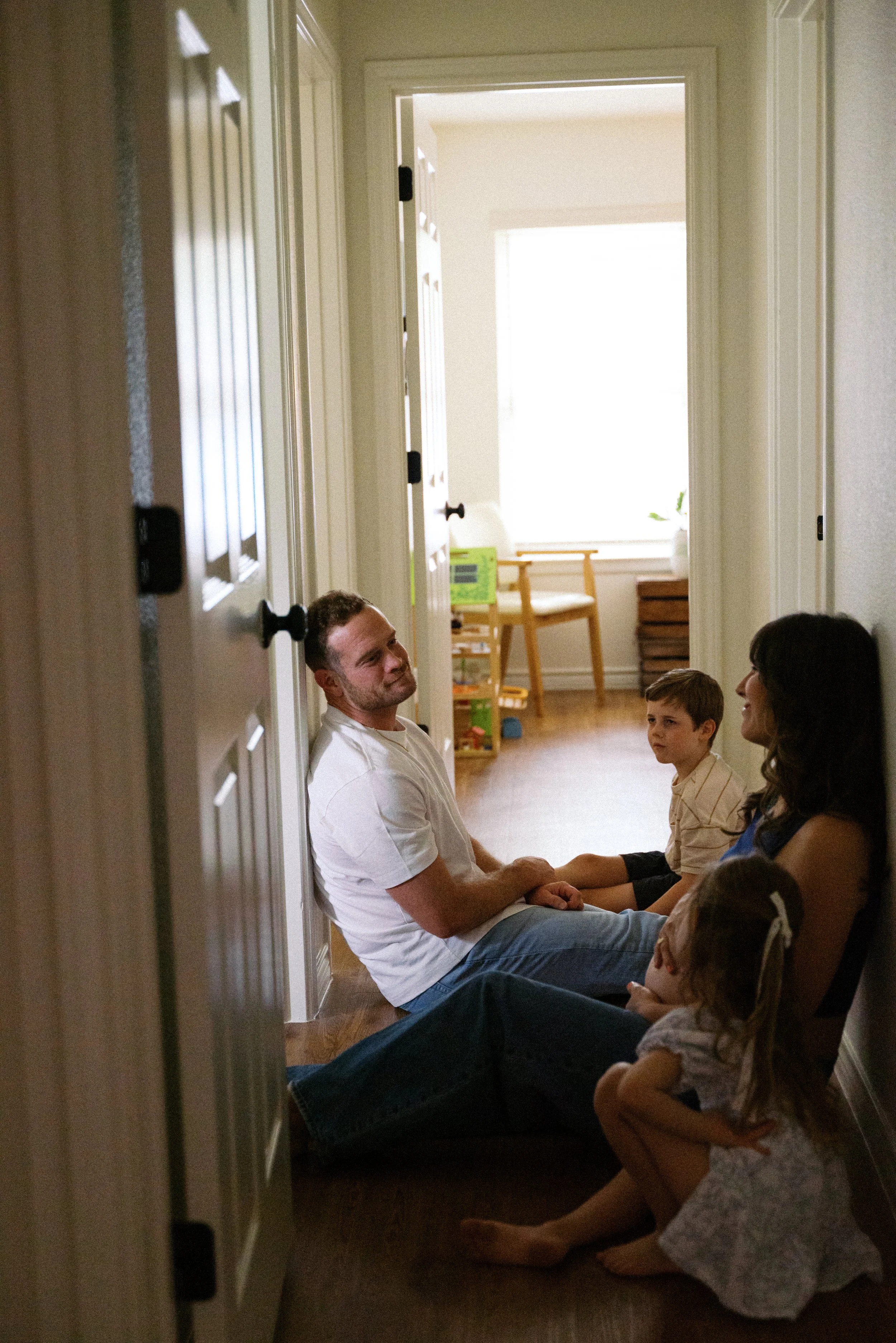Family sitting together on the hallway floor, engaging in conversation.