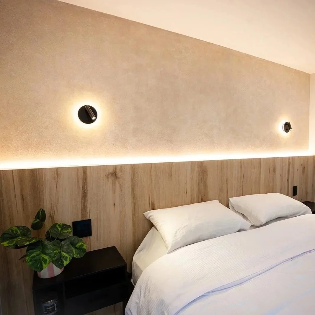 Bespoke master bedroom renovation with custom wood headboard, warm cove lighting, and luxury finishes.