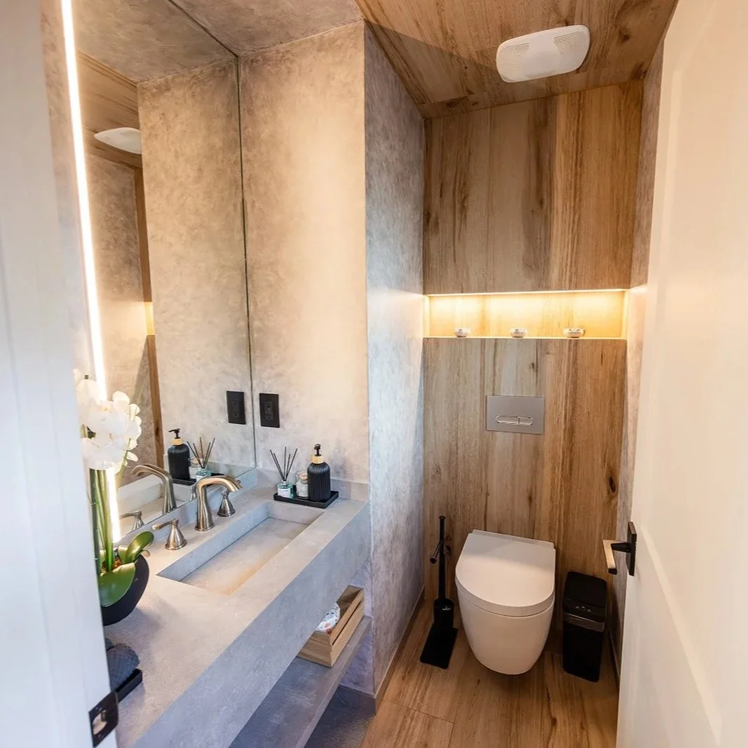 High-end guest bathroom renovation in Grand Cayman featuring custom wood paneling, warm recessed lighting, and a modern floating vanity.