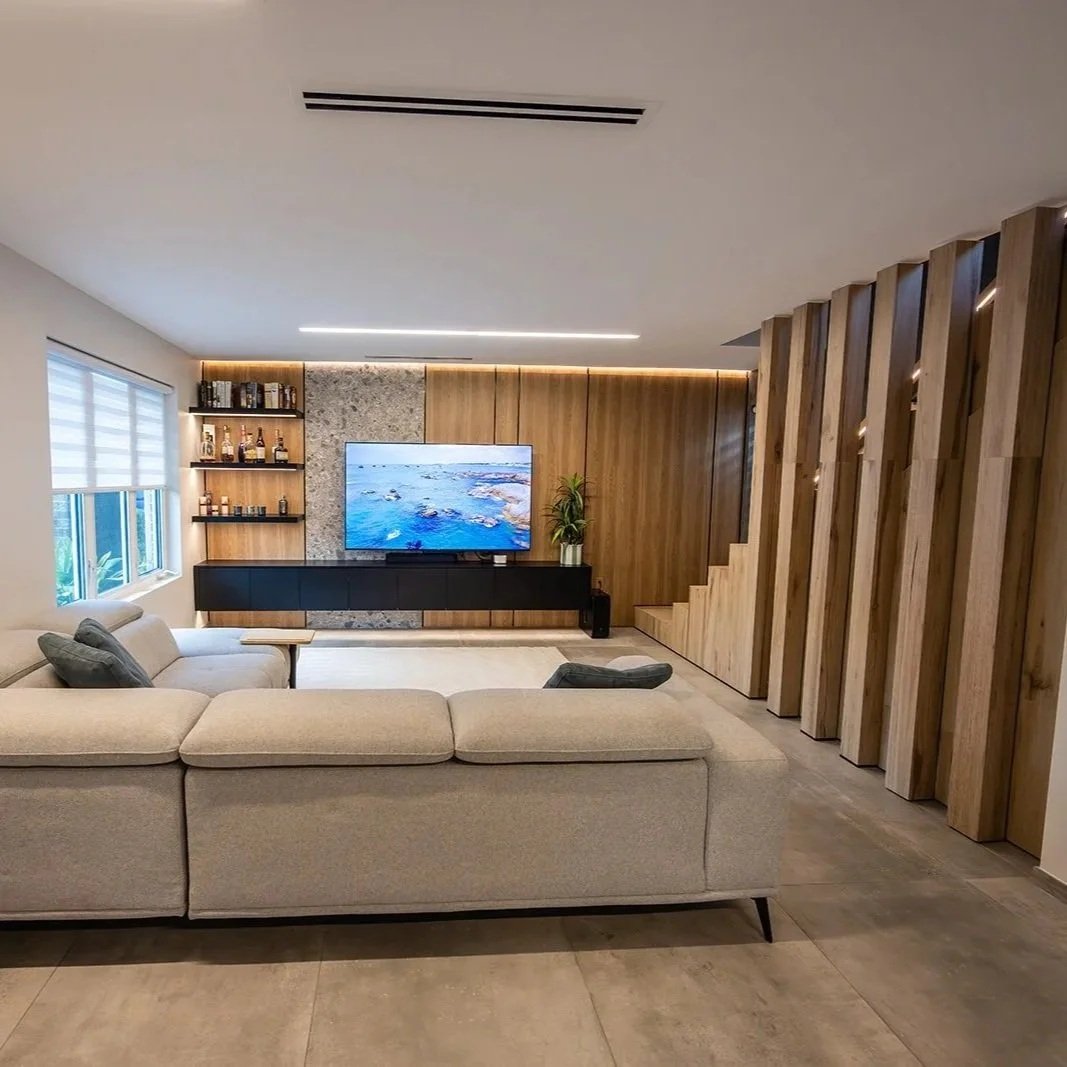 Open-plan luxury interior renovation showing modern living space with custom wood slat feature wall and designer furniture.