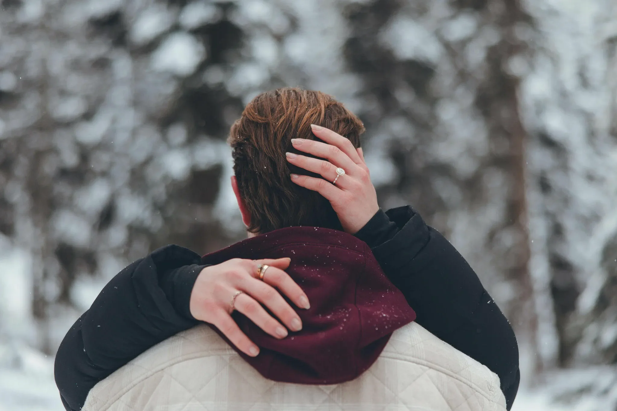 122_couple-engagement-hug-snowy-mountain-forest.webp