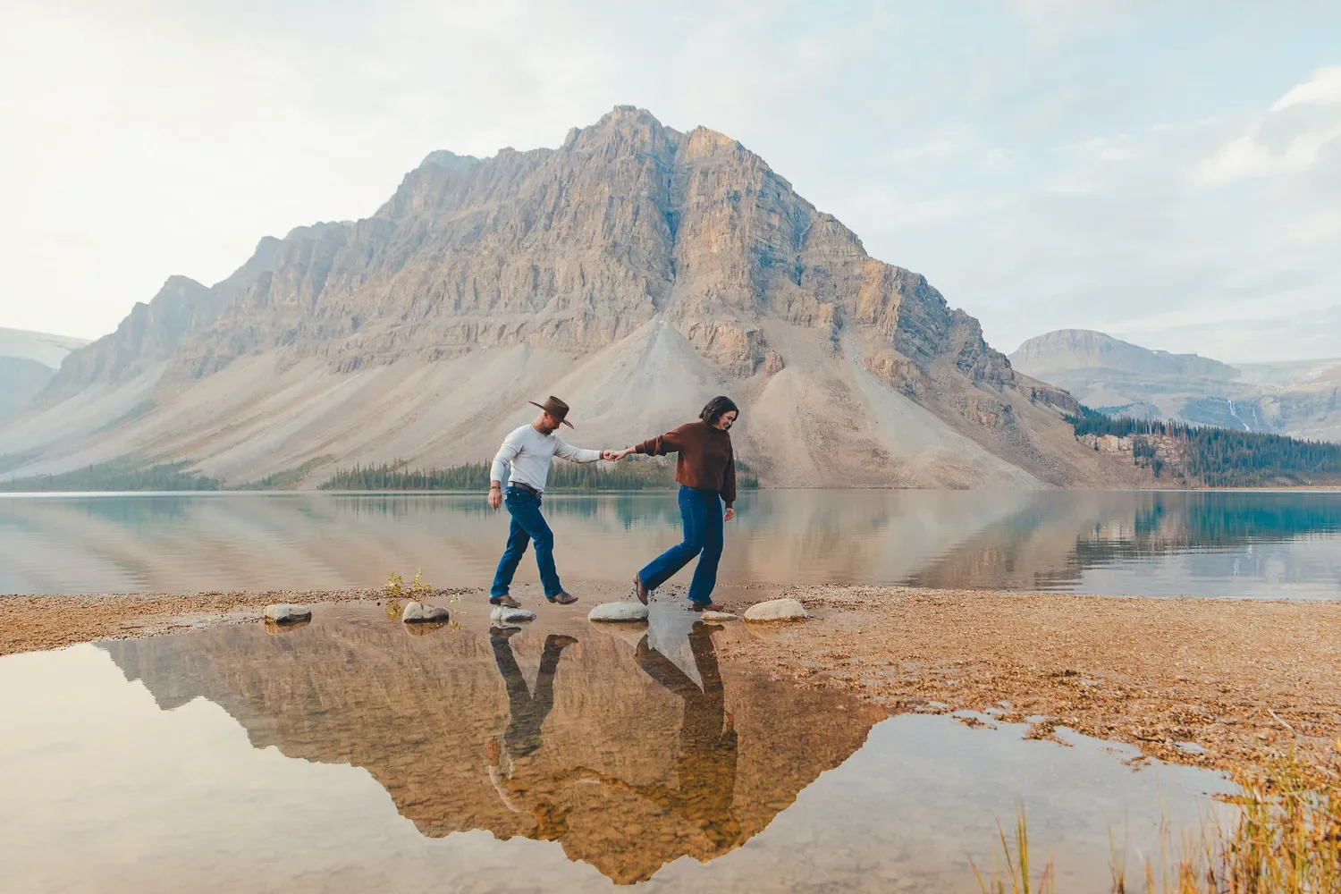 119_couple-walking-stepping-stones-reflection-bow-lake-banff.webp