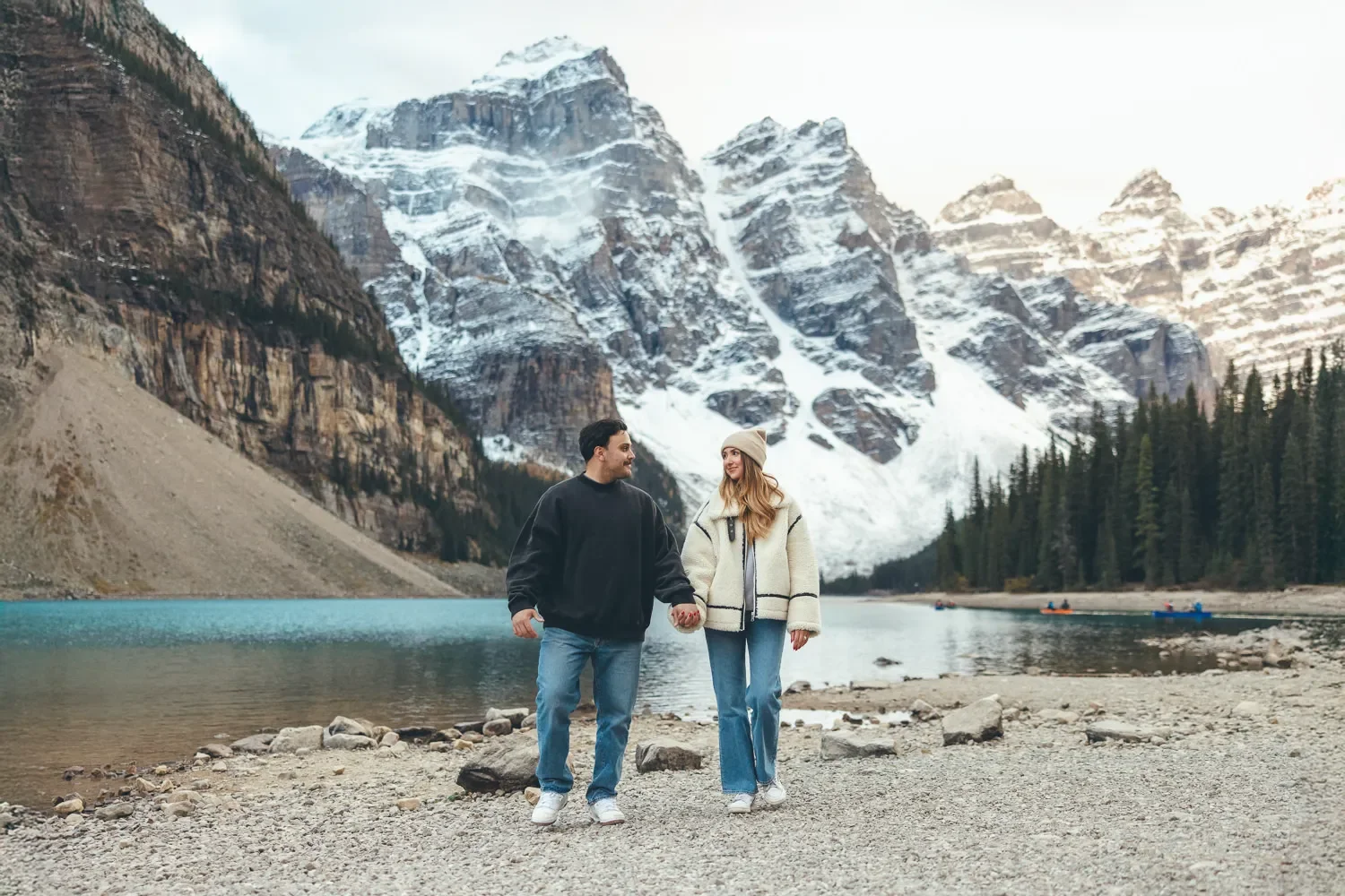 110_couple-walking-shoreline-moraine-lake-banff-snowy-mountains.webp