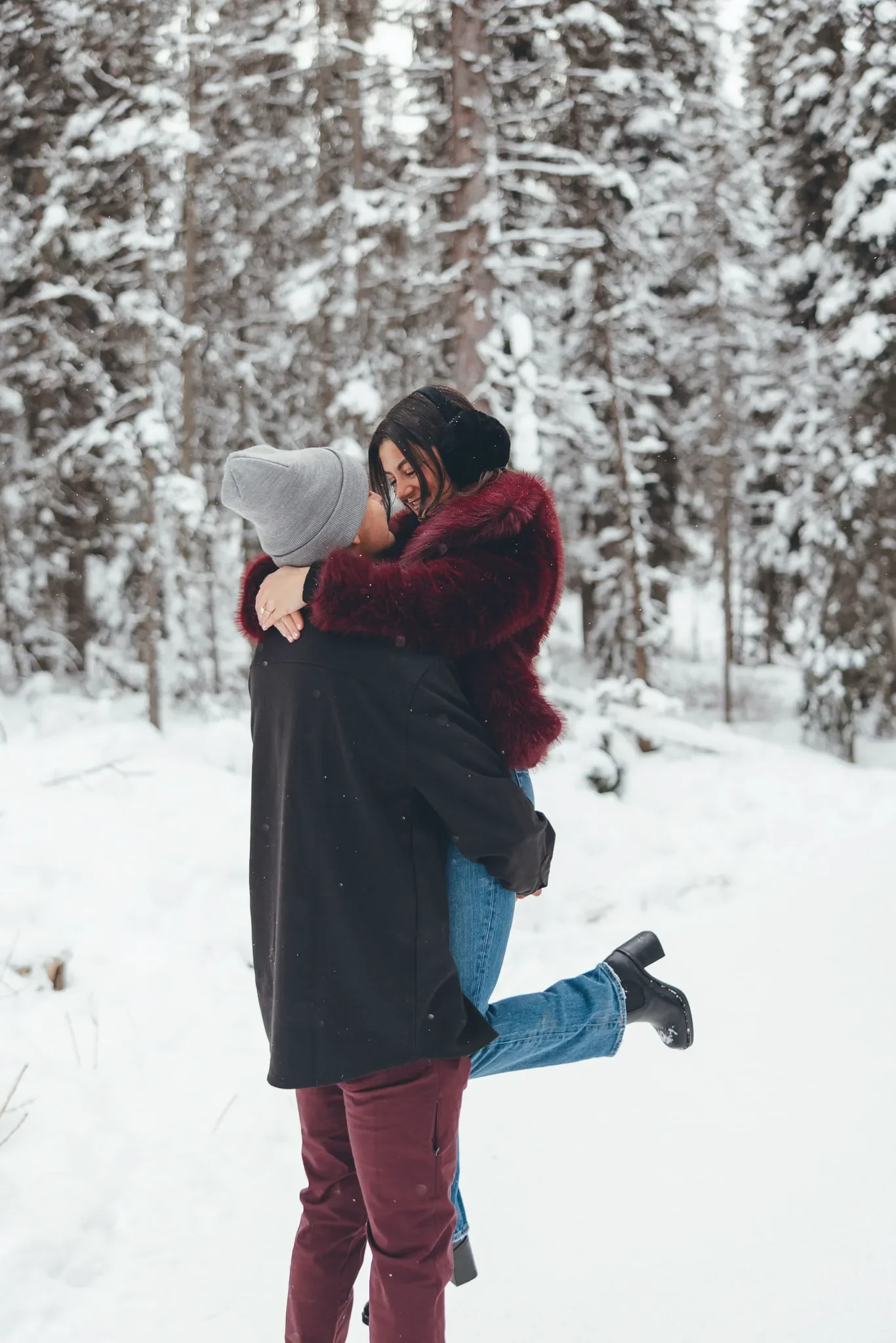 147_couple-engagement-lifting-snowy-forest-winter.webp