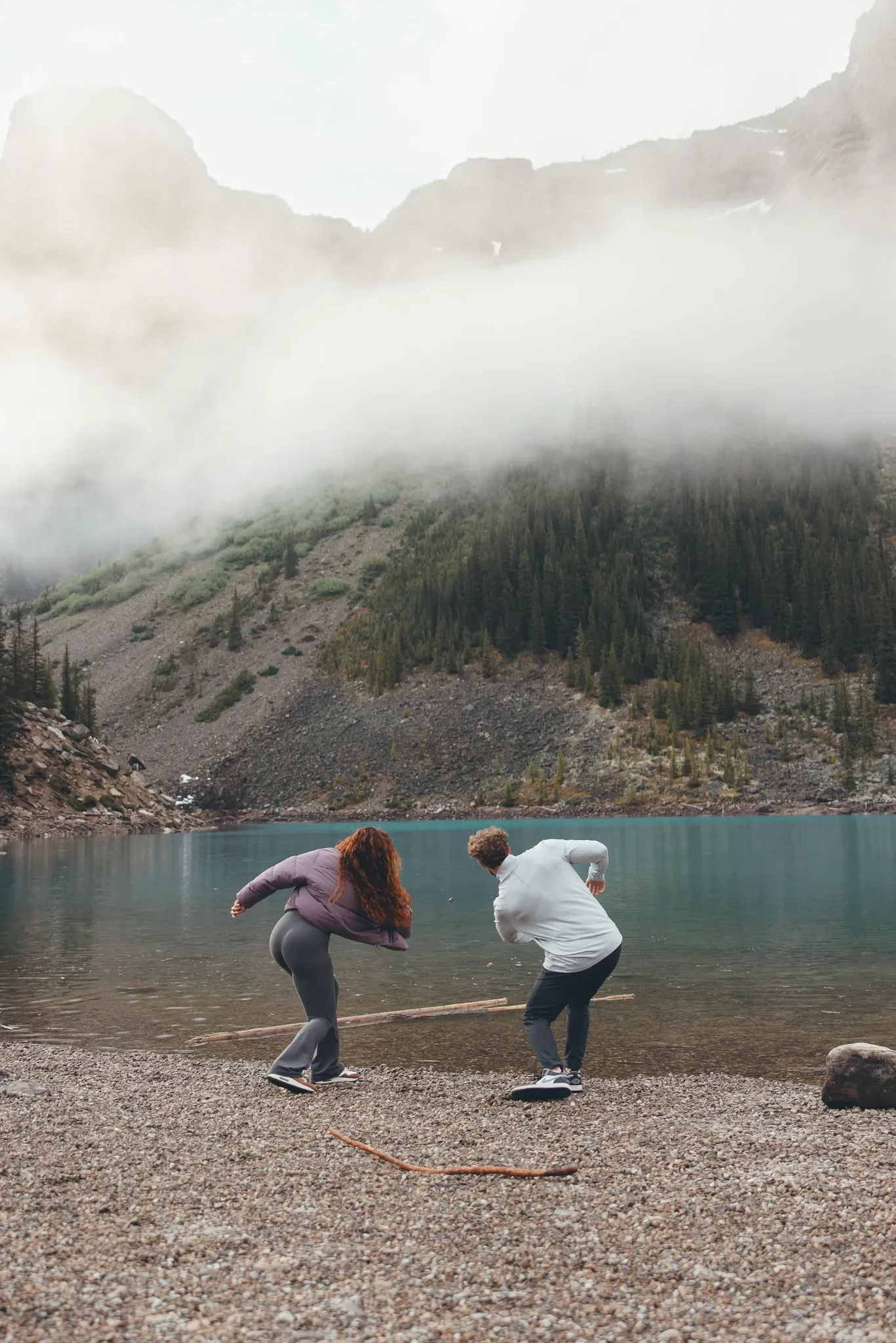 145_couple-throwing-rocks-alpine-lake-canadian-rockies.webp