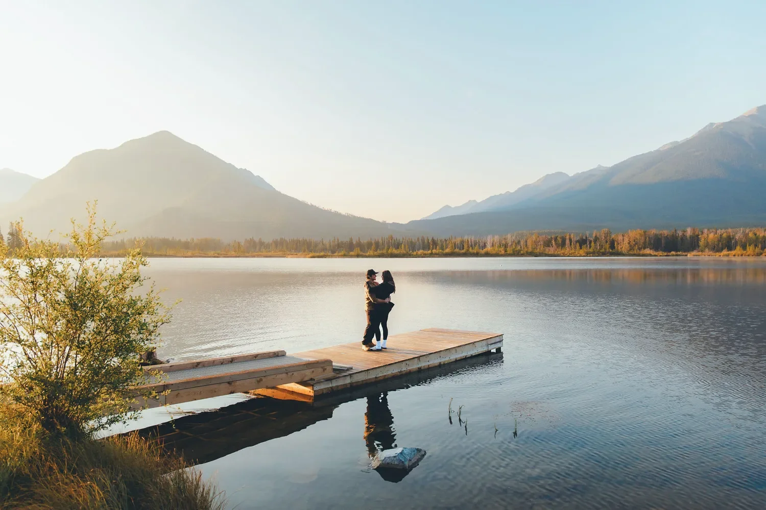 112_Couple-Standing-On-Wooden-Dock-At-Alpine-Lake-In-Canadian-Rockies-At-Golden-Hour.webp