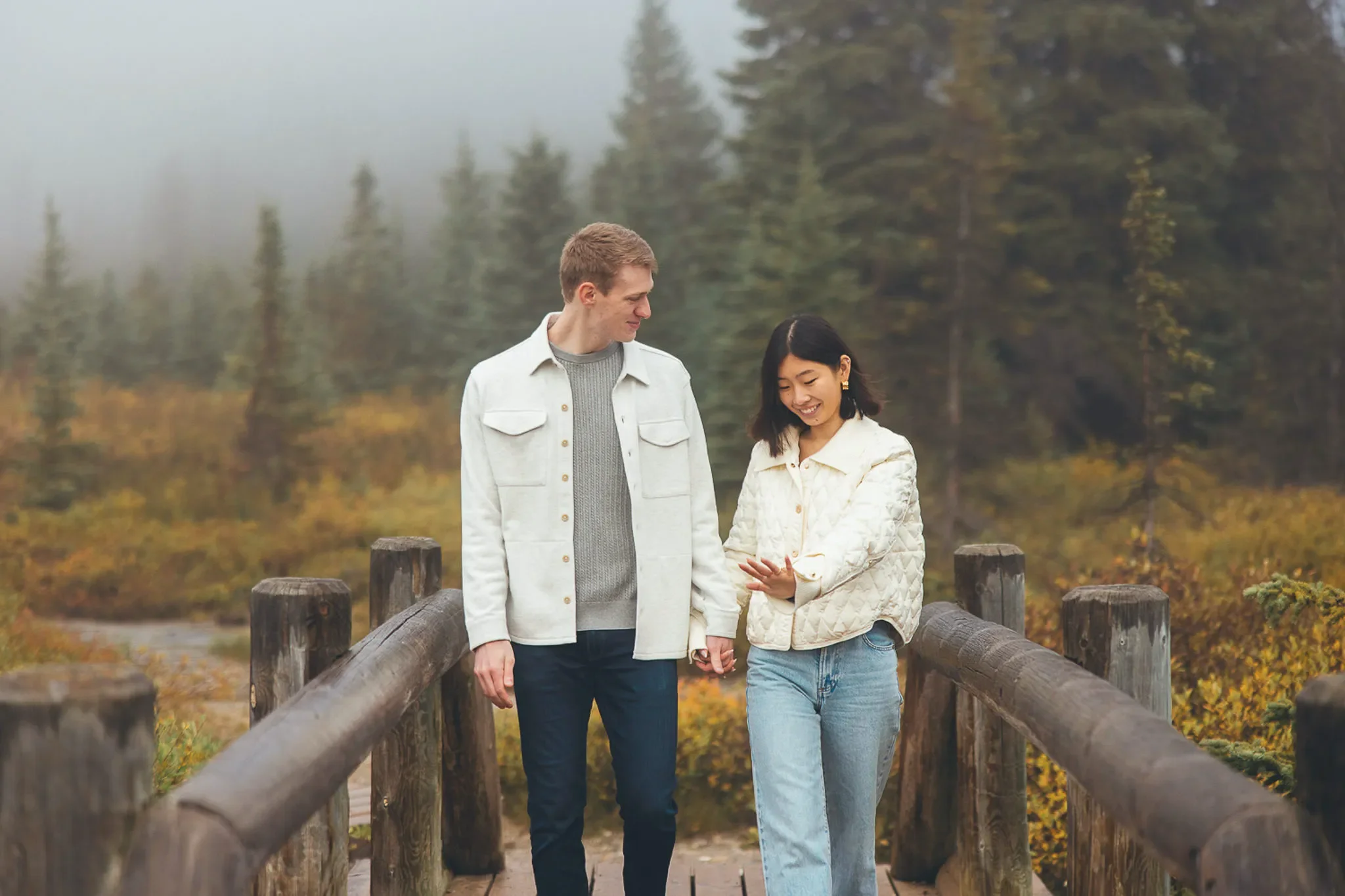 111_Couple-Engagement-Walking-Wooden-Bridge-Misty-Forest.webp