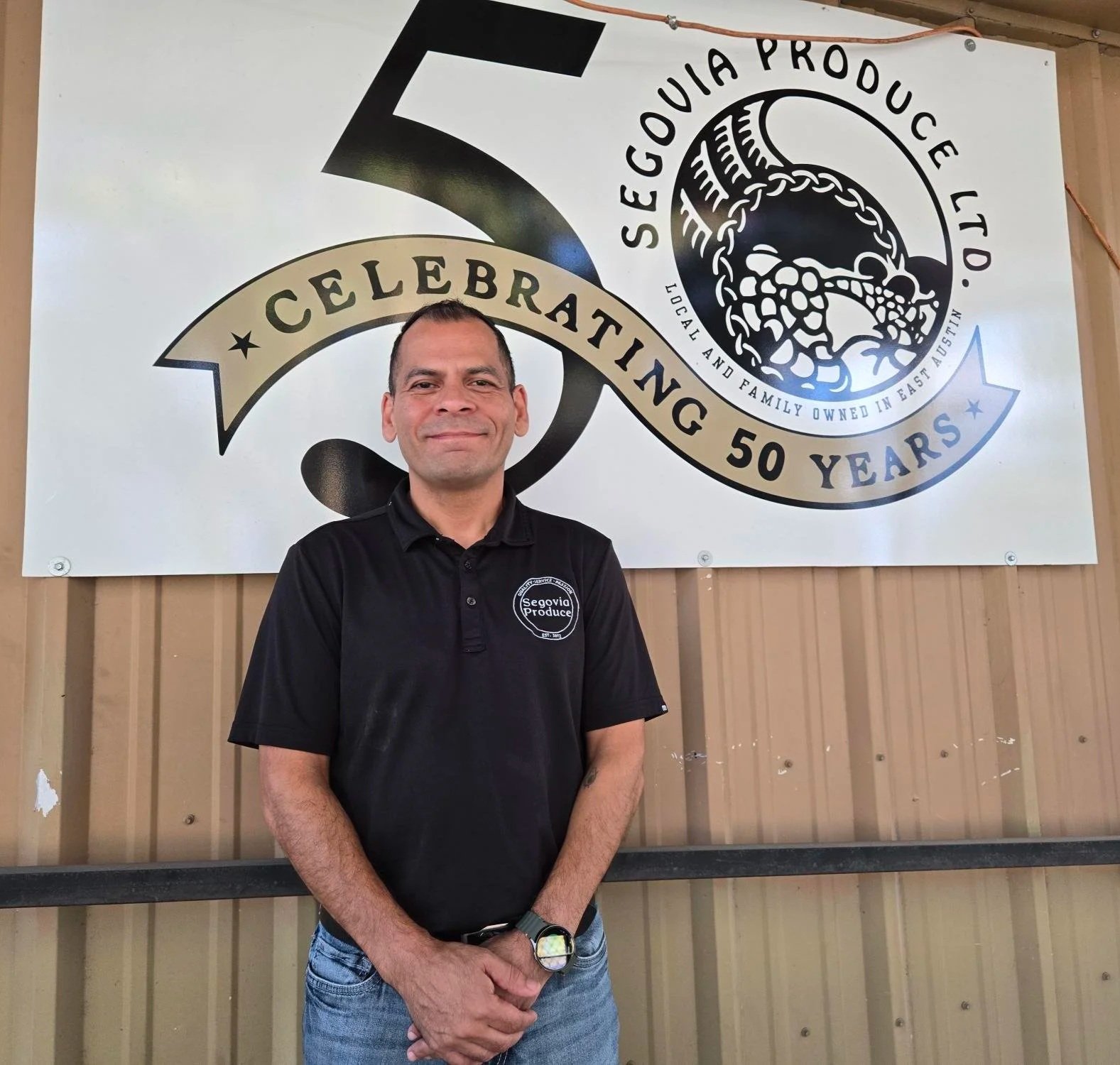 Frank Gomez, Jr. with banner that reads "Segovia Produce Ltd. Celebrating 50 Years"